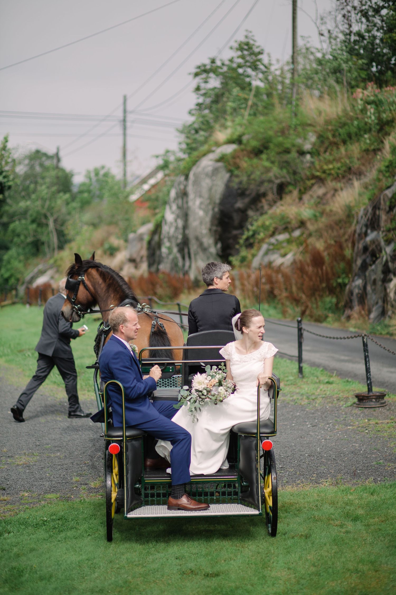 Wedding couple riding in vintage pedicab along gravel path with rocky landscape.