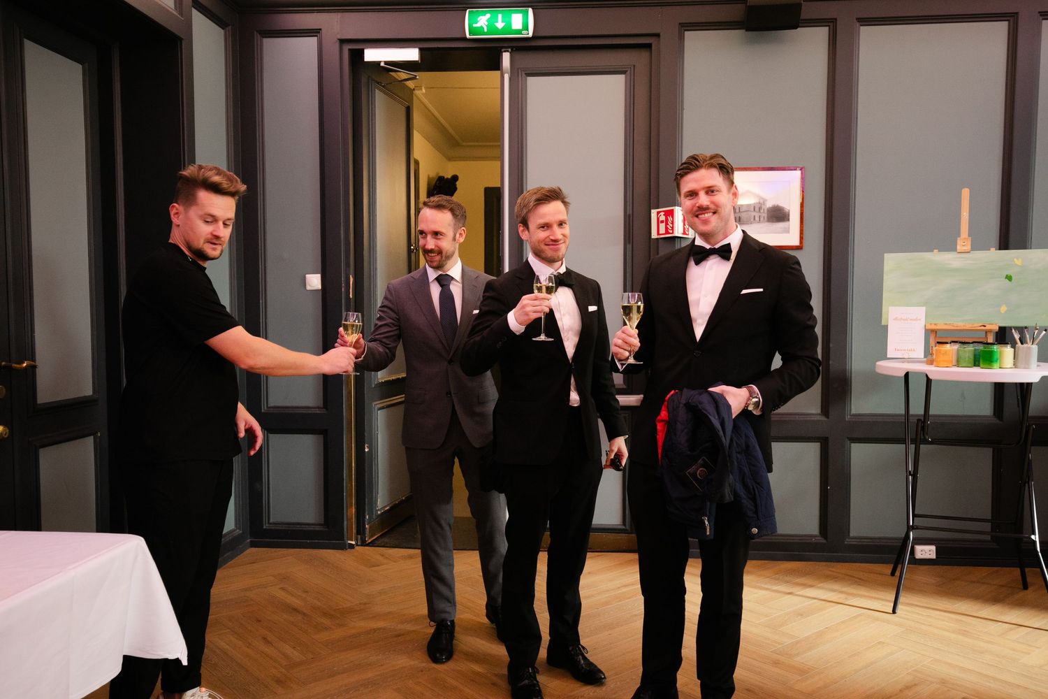 Group of formally dressed guests laughing and socializing at an indoor event.