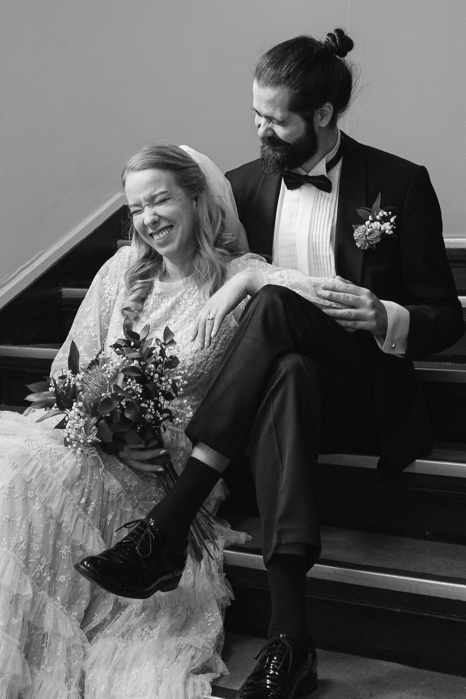 Couple in wedding attire sharing joyful moments on wooden church pews.