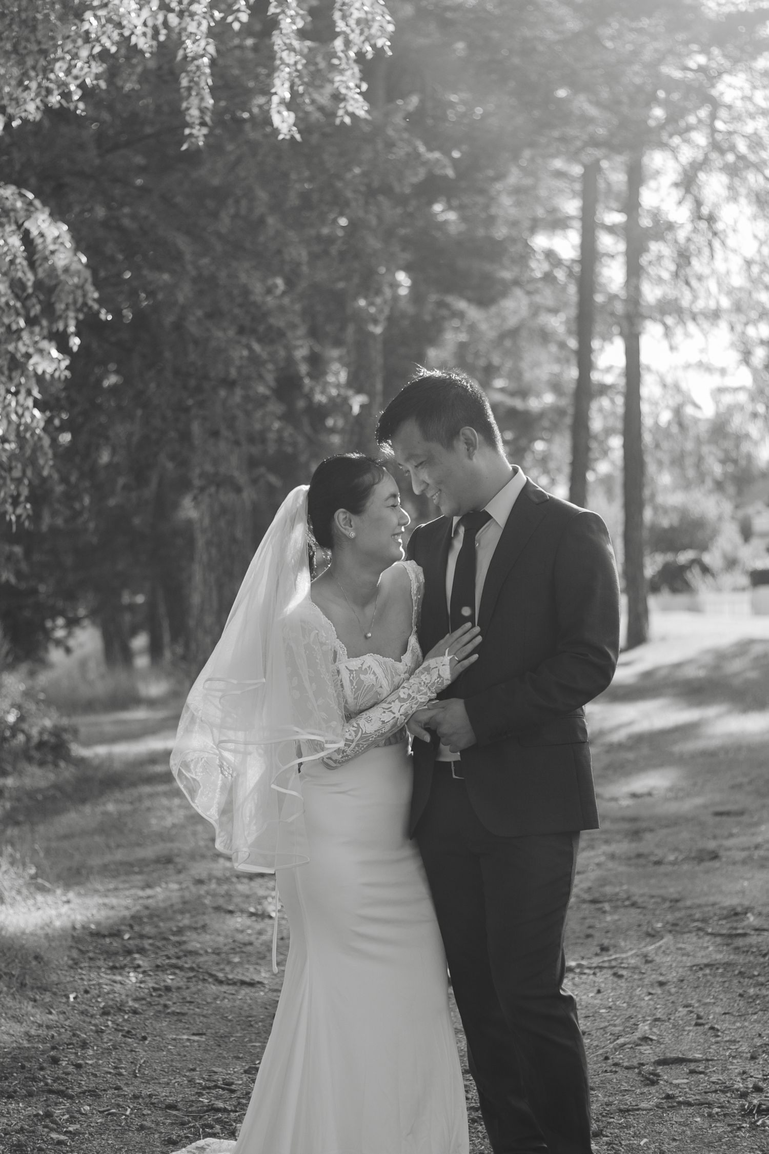 A black and white photo captures tender moments between newlyweds in a forest setting.