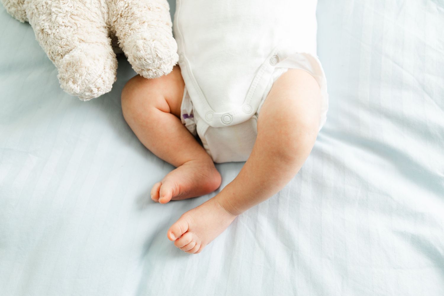 A series showing small hands and feet against crisp white bedding.