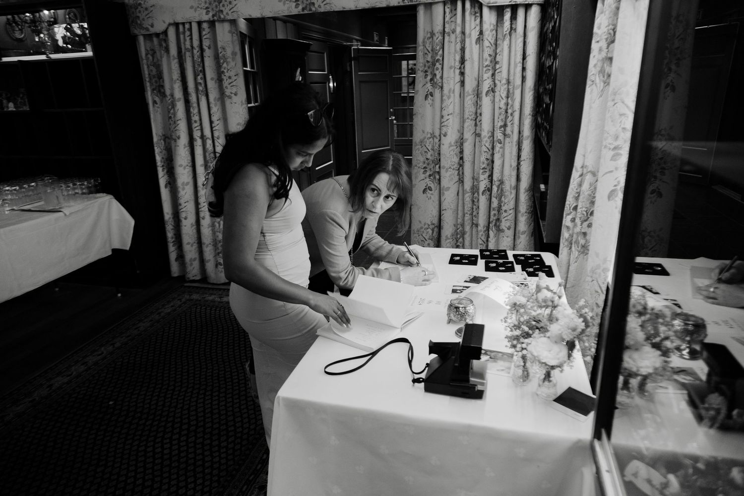 Black and white image of a reception table setup with decorative elements.