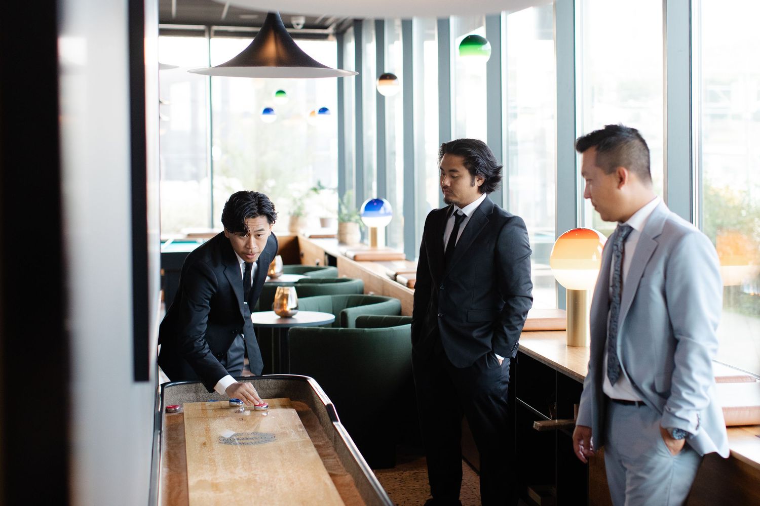 Stylish wedding party members socializing in a modern venue with large windows.