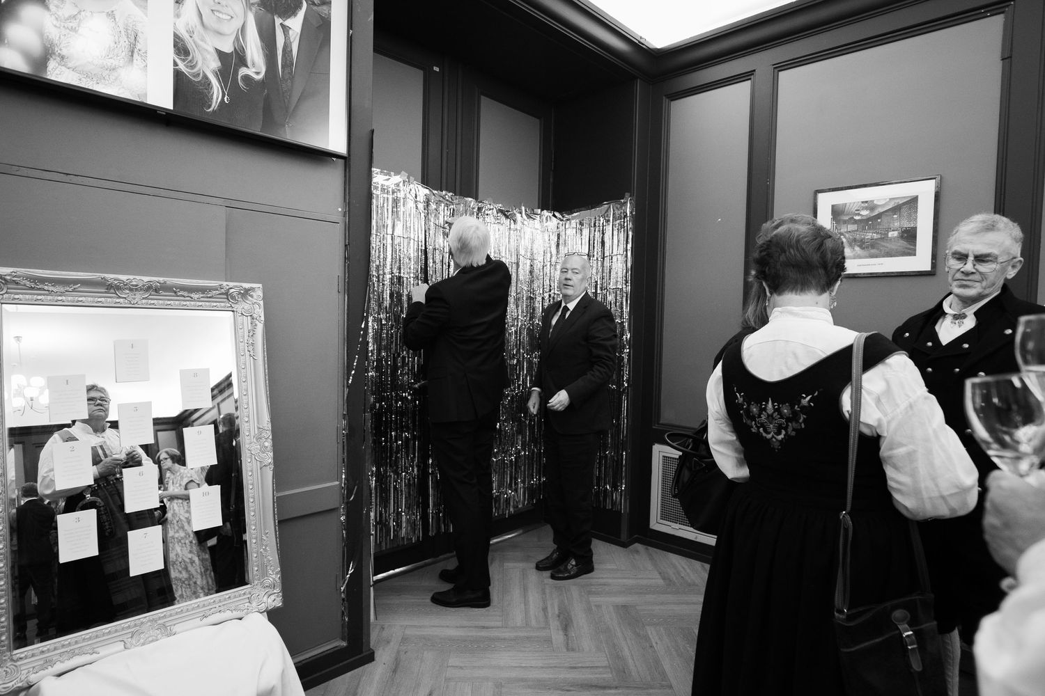 Black and white photo of guests viewing artwork at a formal gallery reception.