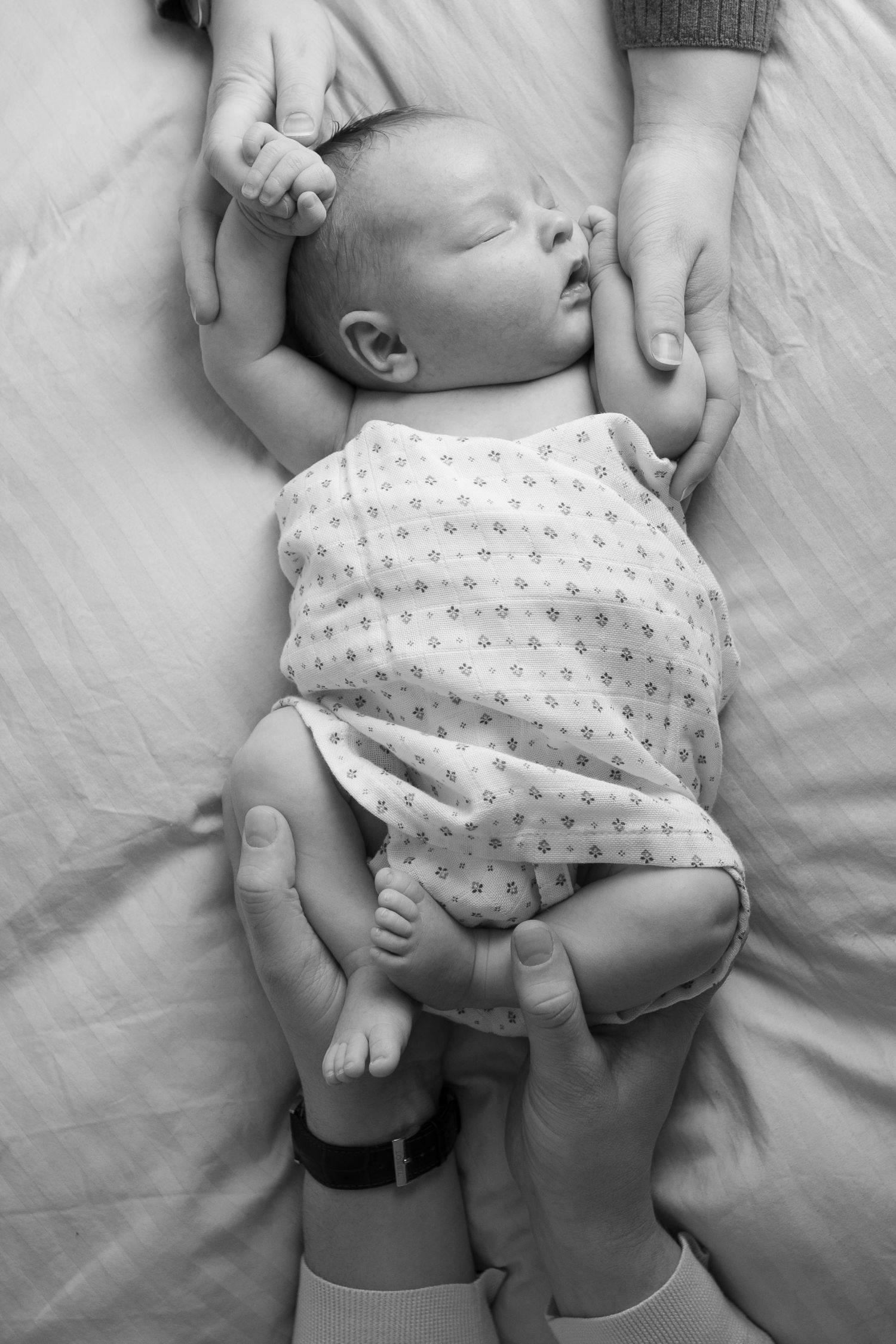 A series of intimate black and white photos showing a baby in a polka dot onesie.