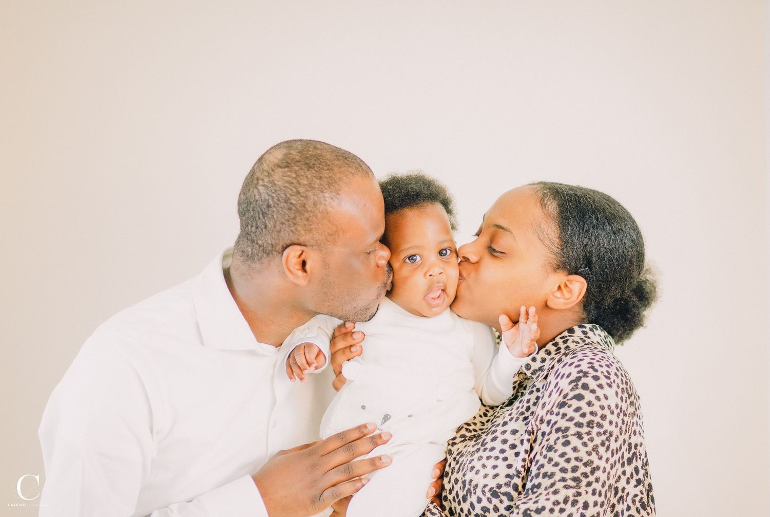Family sharing tender moment against neutral background.