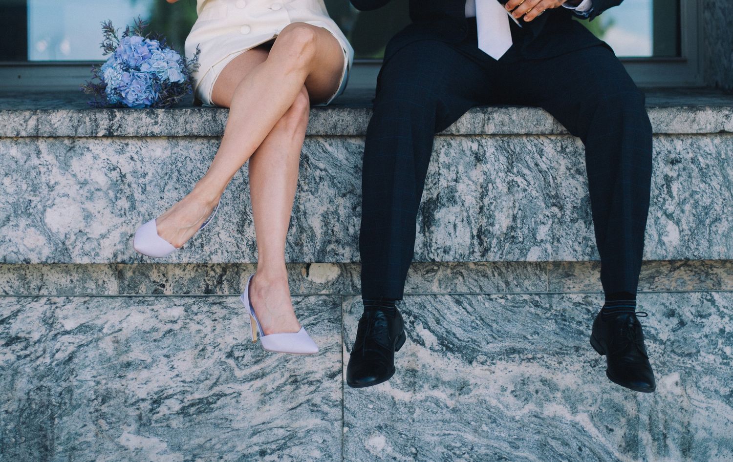 Close-up details of legs and feet on marble steps during an elegant photoshoot.
