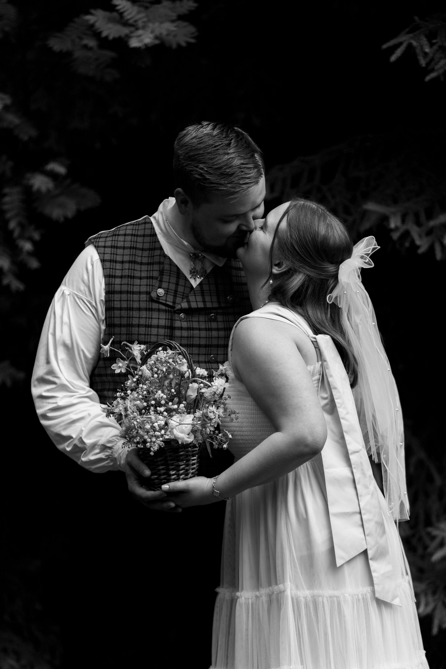 Black and white artistic wedding portrait showing an intimate moment with floral bouquet.