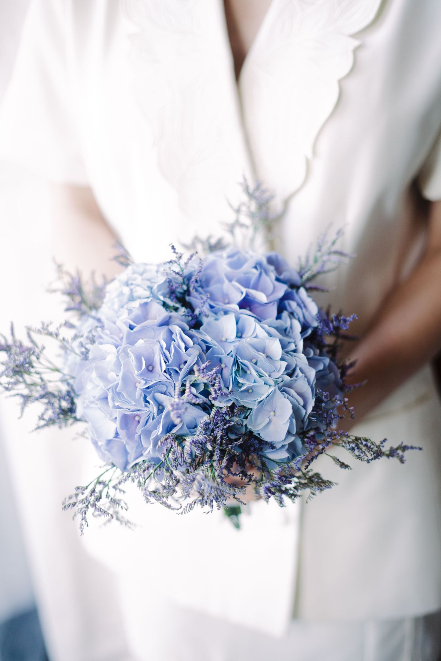 Delicate blue hydrangea and lavender bouquet arrangement against white background.