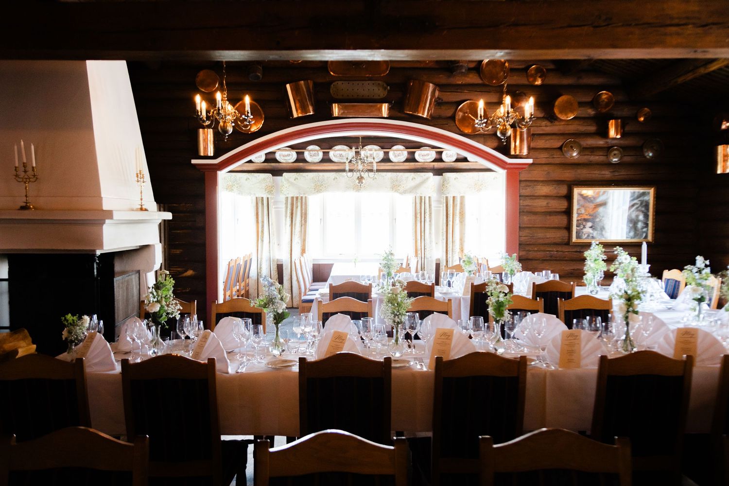 Rustic wedding reception venue with wooden beams and romantic candlelight decoration.