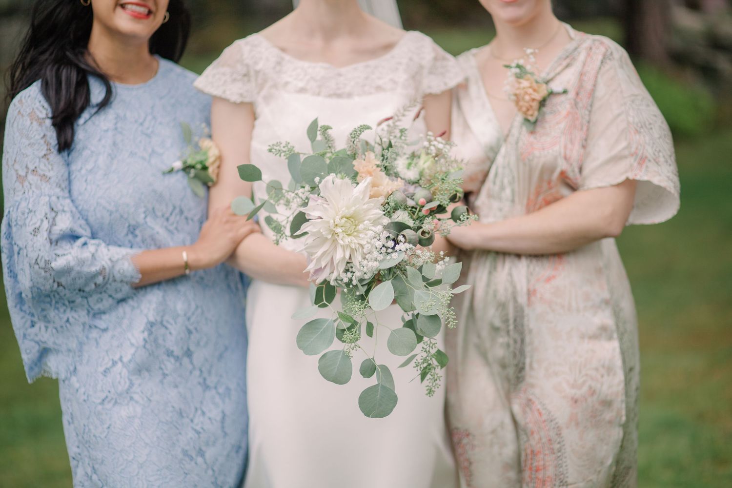 Wedding party members holding bouquets of white and green flowers.