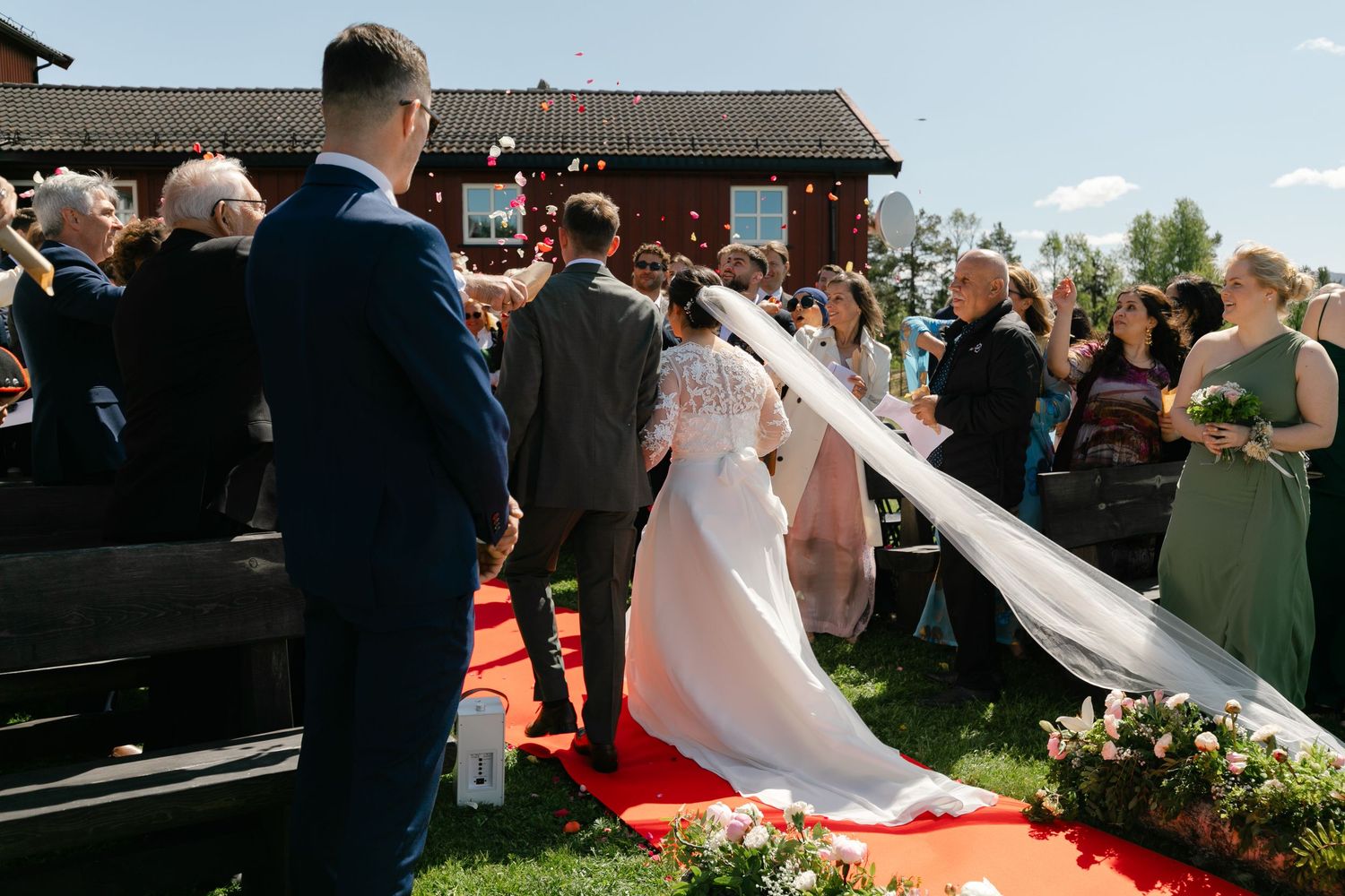 Wedding ceremony guests gather outdoors on a sunny day with mountains in the background.