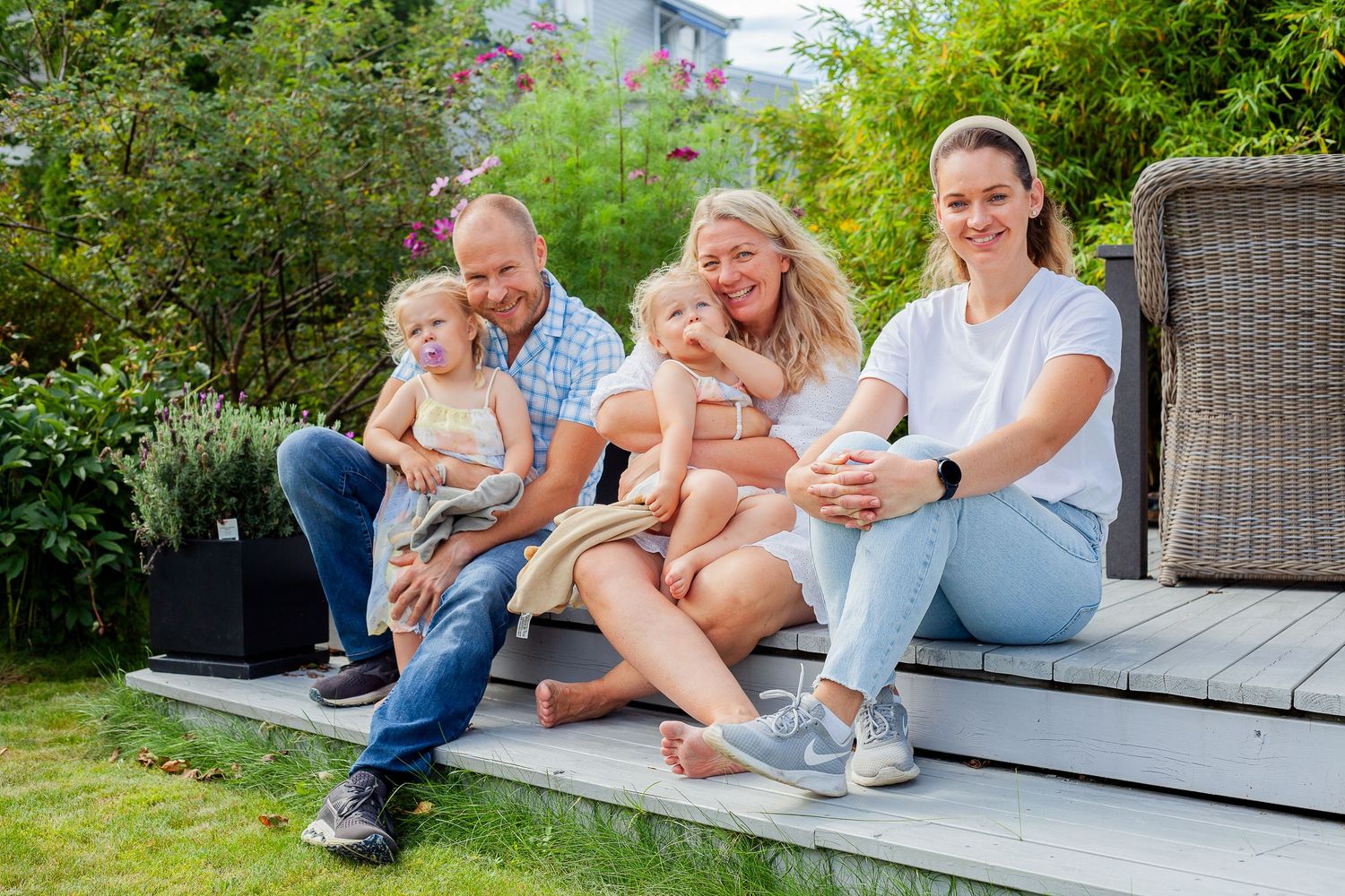 Family relaxing together on an outdoor deck or patio surrounded by greenery.