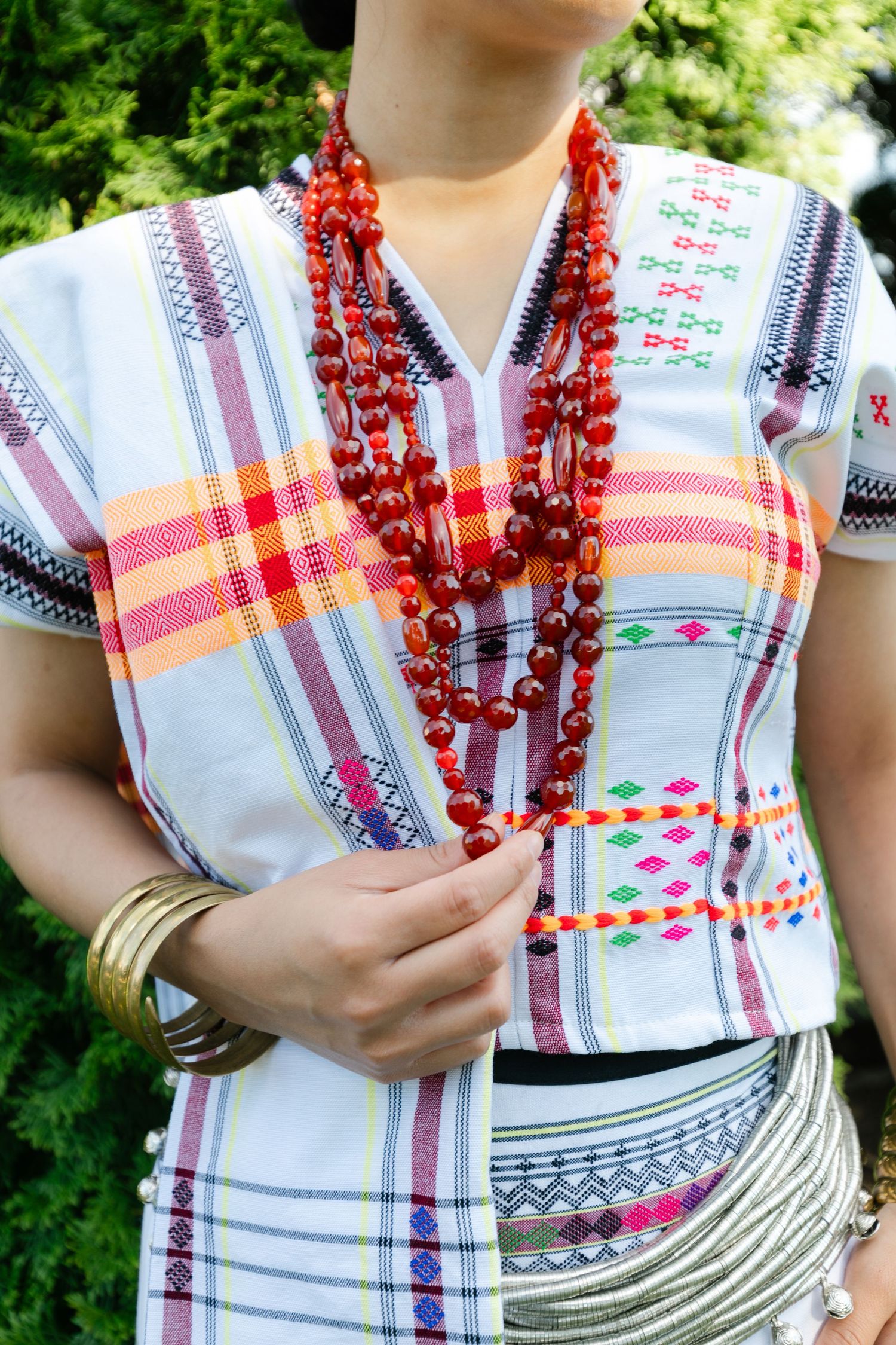 Close-up of traditional Filipino clothing with colorful patterns and red beaded necklace.
