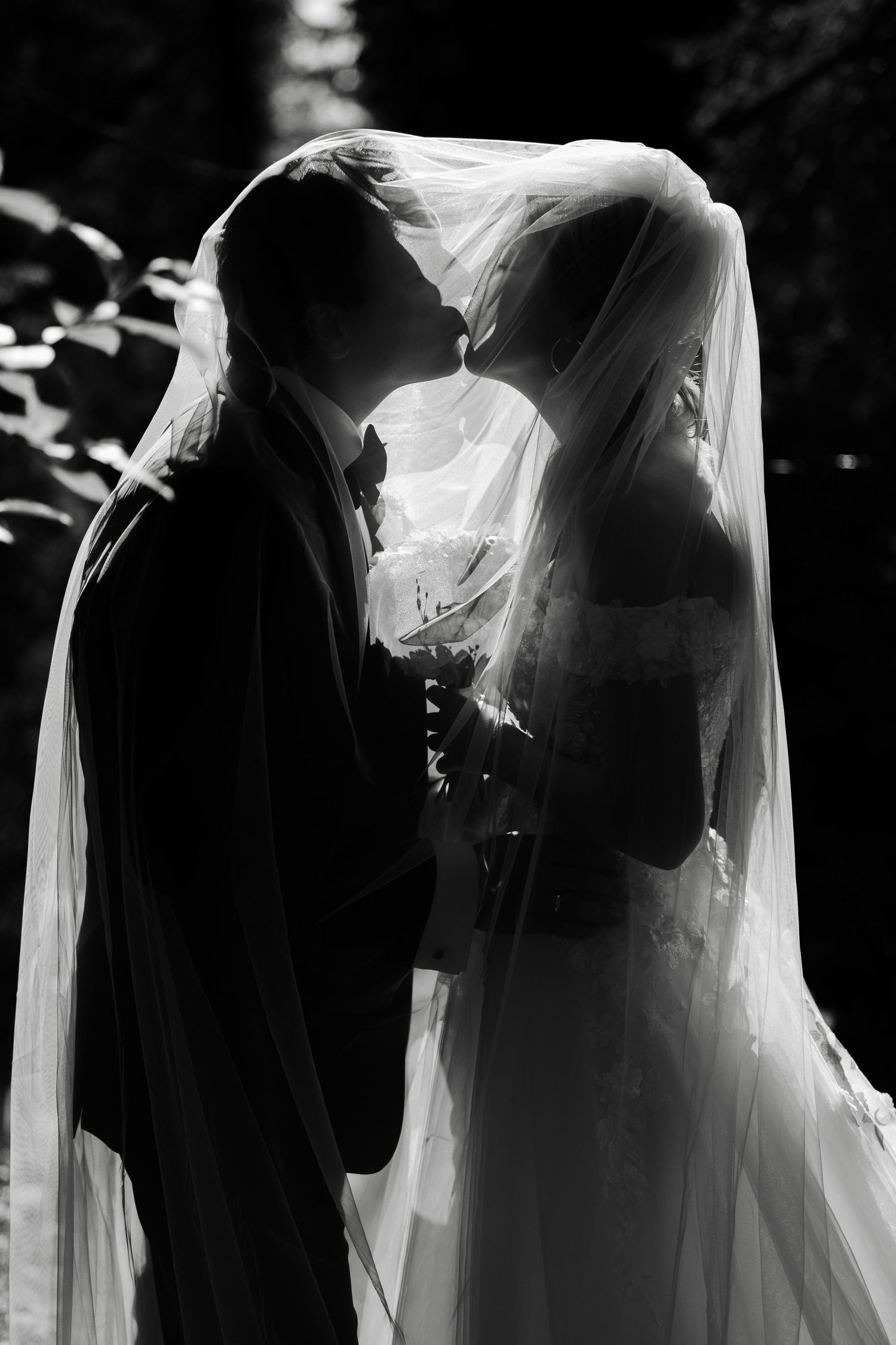 A romantic black and white wedding photo sequence showing silhouettes of a couple kissing under a flowing bridal veil.