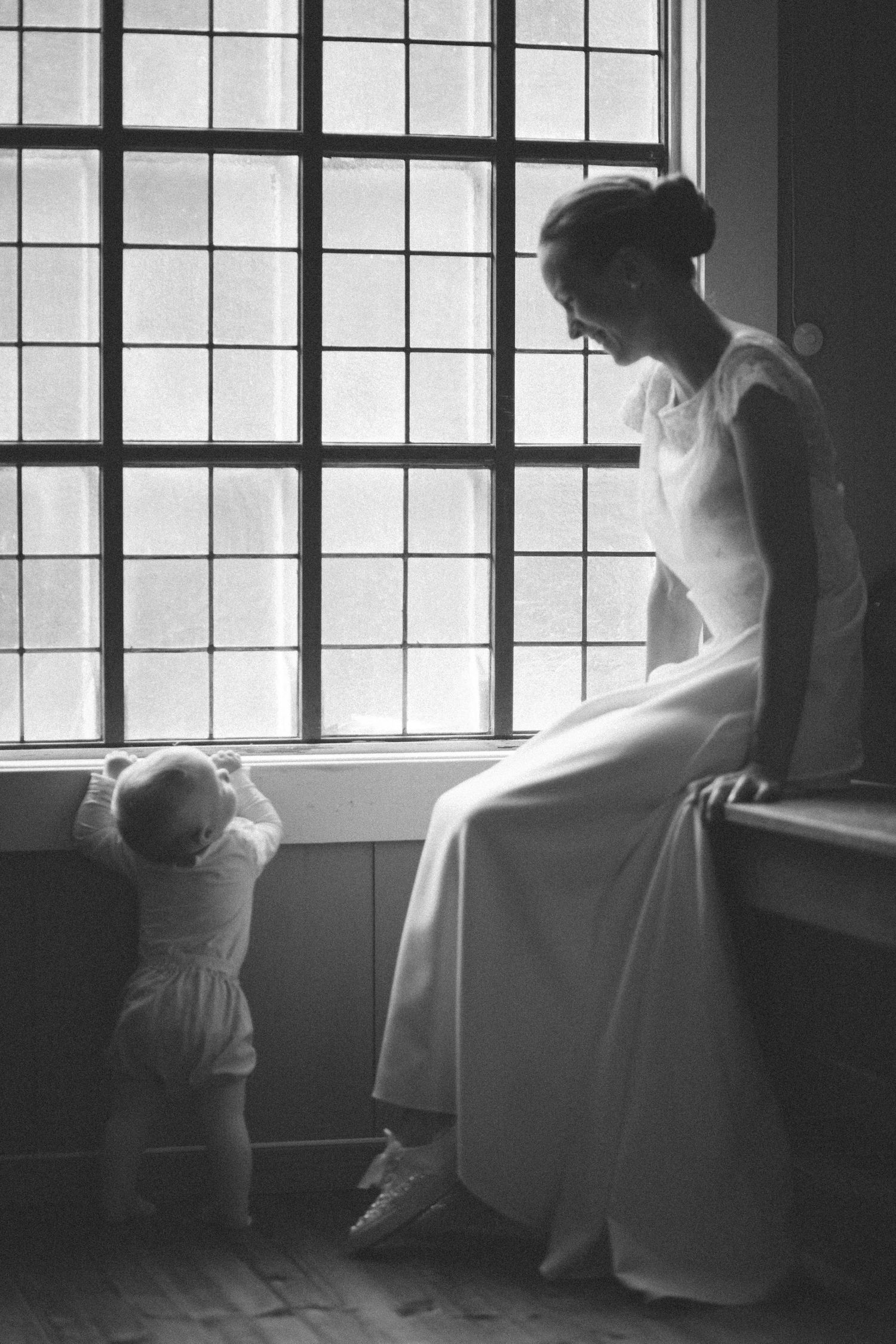 Dramatic black and white window silhouette of bride in wedding dress.