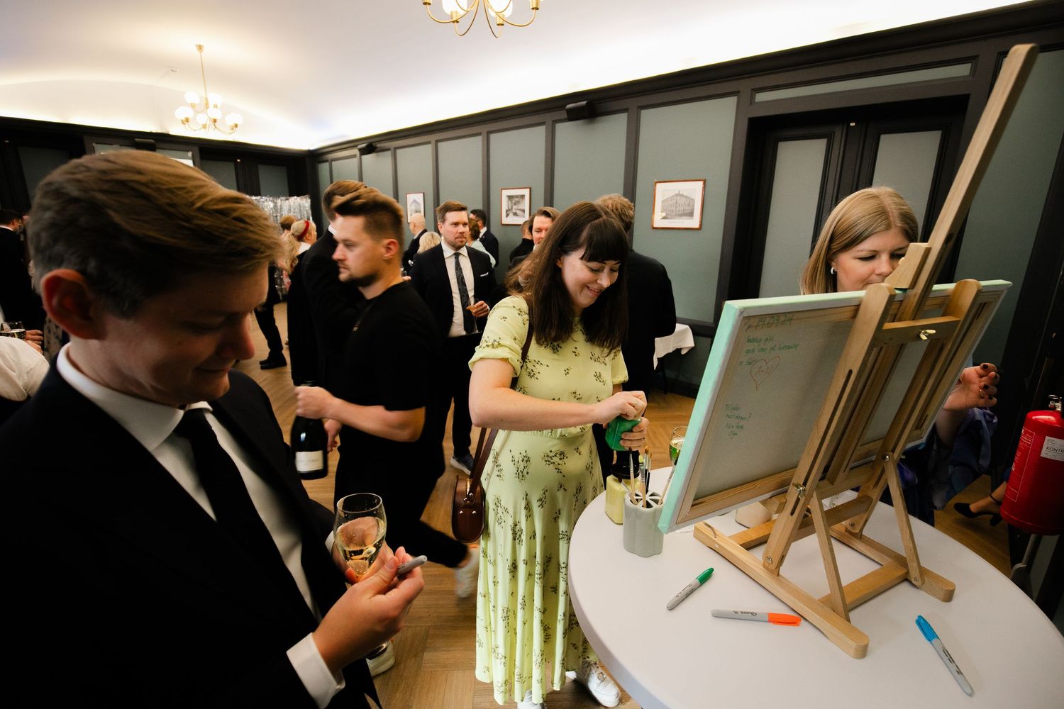 Wedding guests participating in an interactive painting activity at a reception.