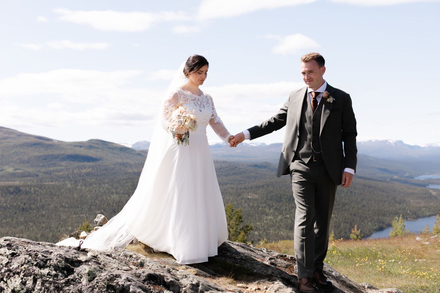 Couple celebrating their wedding day on scenic mountain overlook with lake views.