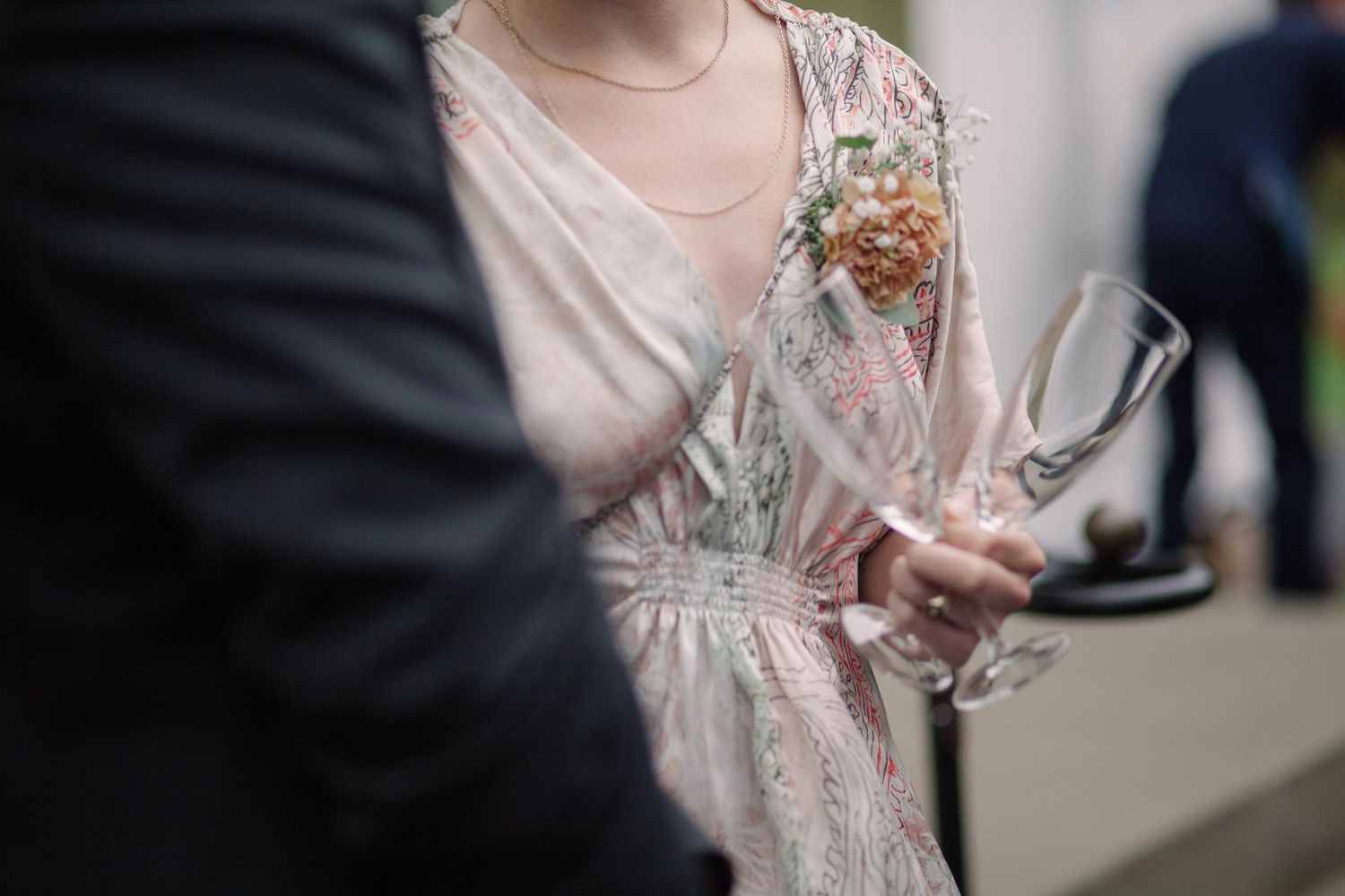 Close-up detail of white wedding dress and shoes on gravel path.