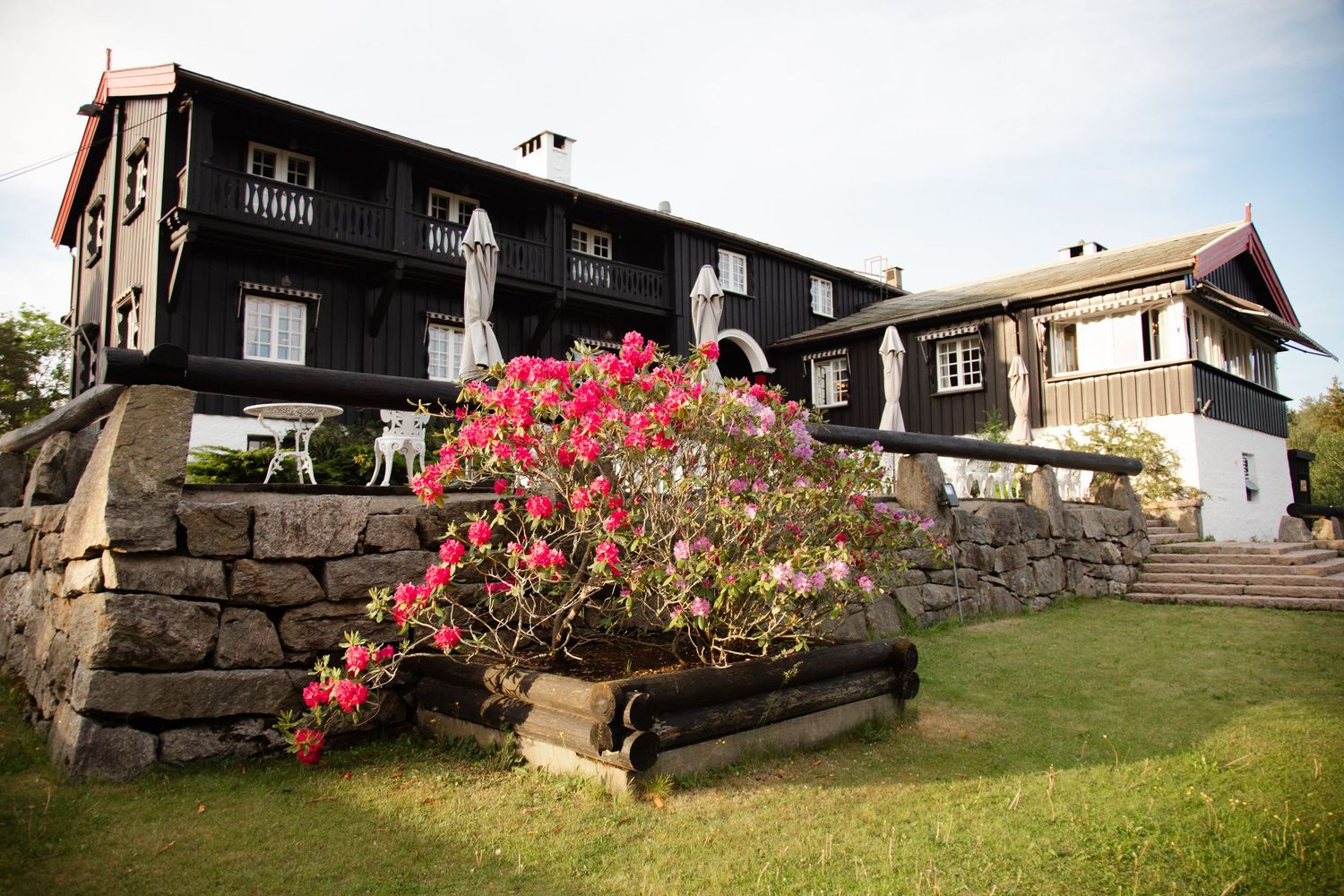 Rustic stone and wood buildings with bright pink flowers in the landscaping.