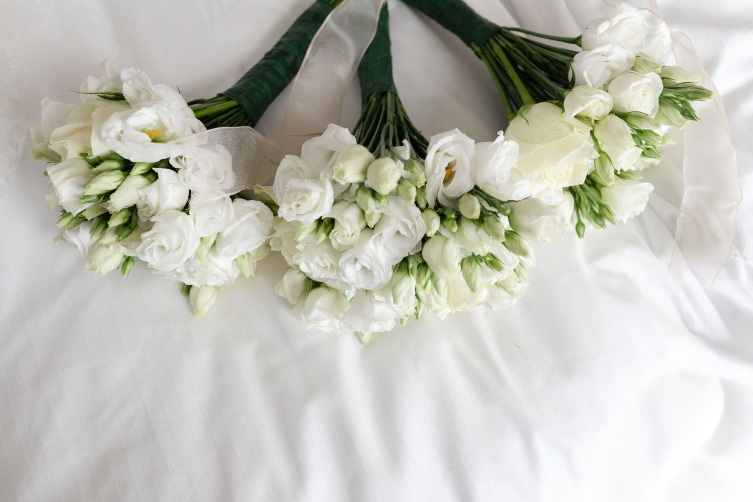 Fresh white floral arrangements laid out on a white surface.