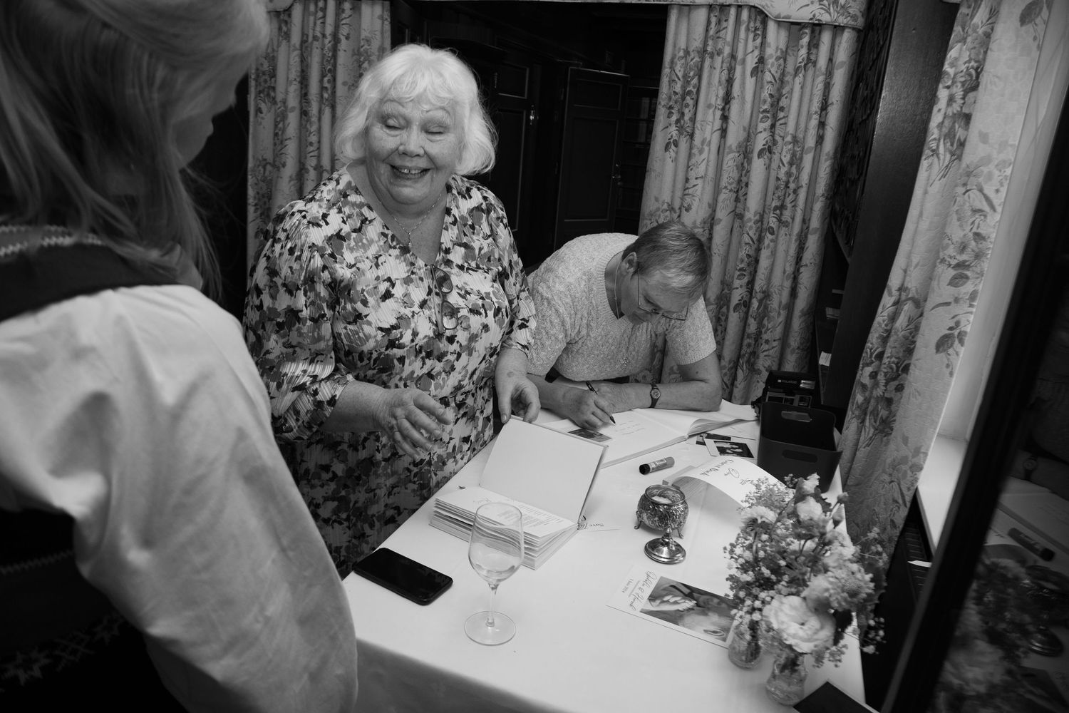 Reception dinner tables with guests and floral centerpieces in black and white.