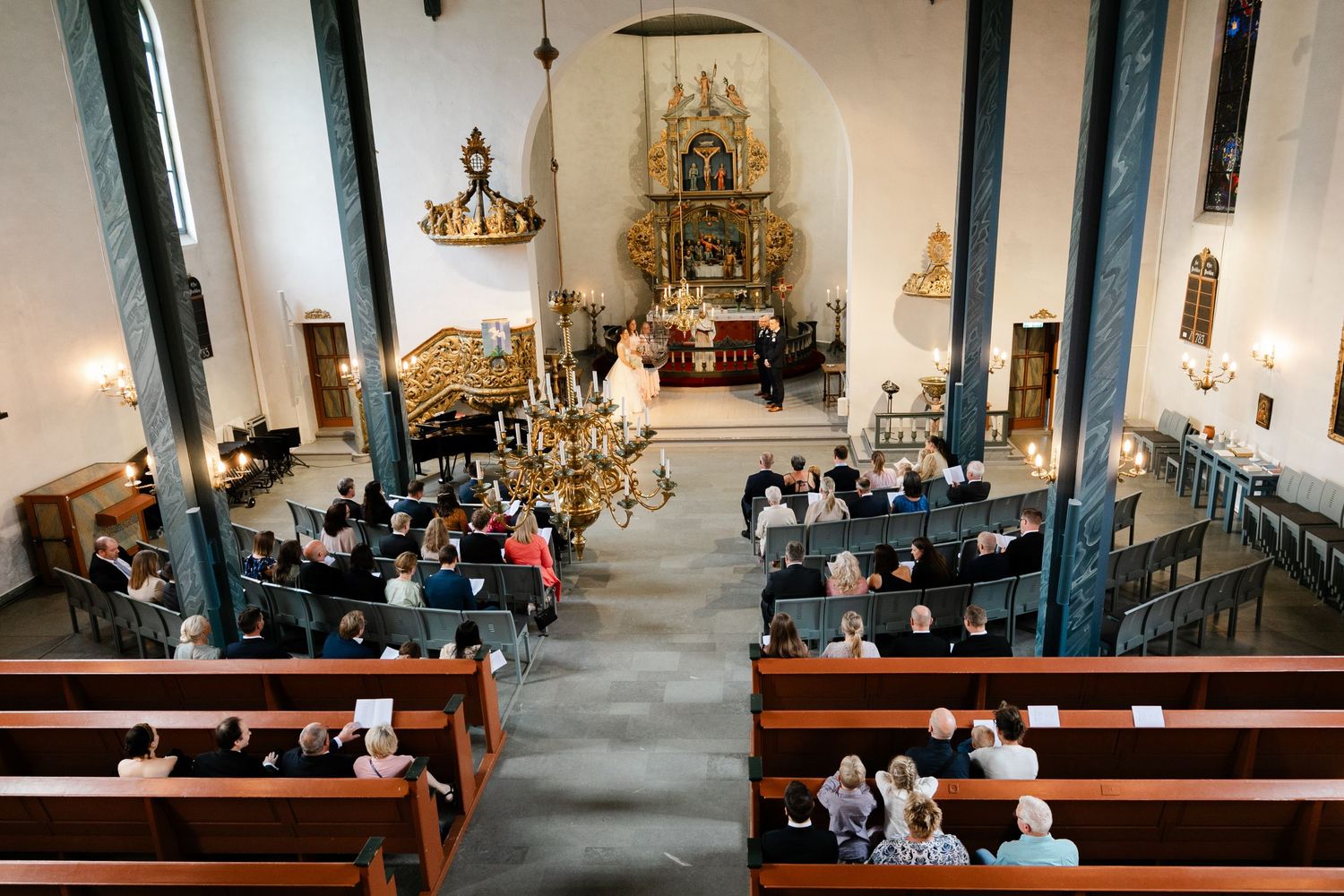 Interior of a traditional church with wooden pews and altar during a wedding ceremony.
