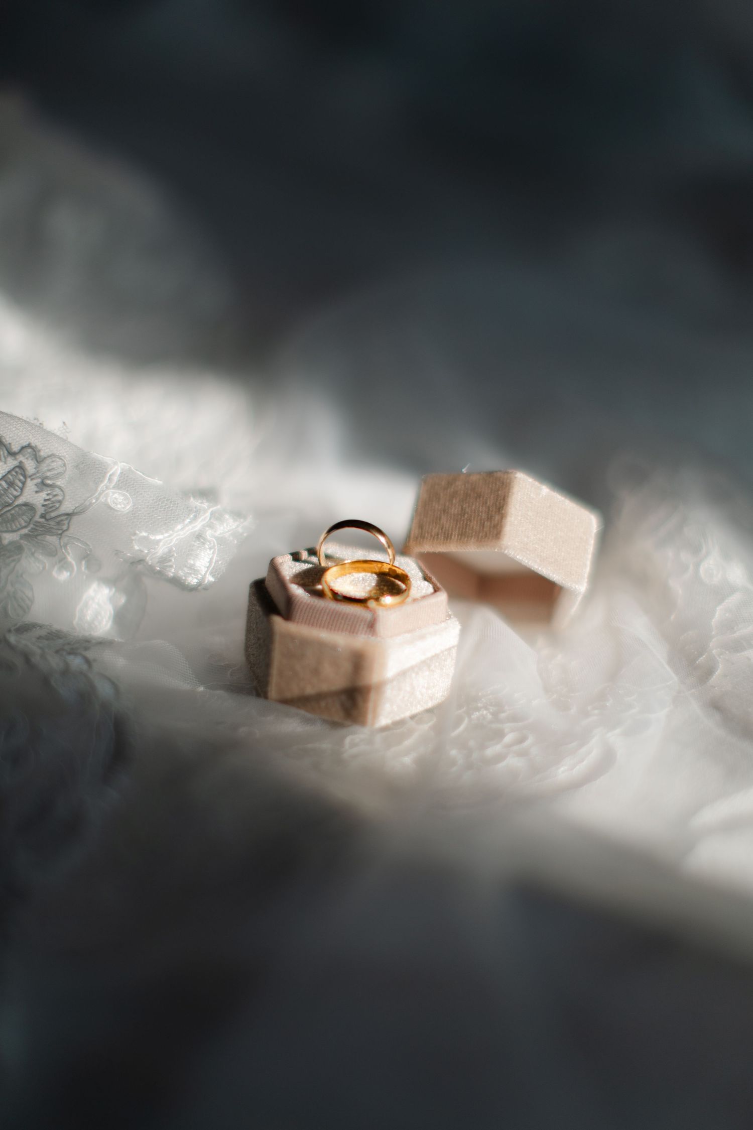 Wedding rings and jewelry boxes photographed in dramatic lighting with smoky atmosphere.