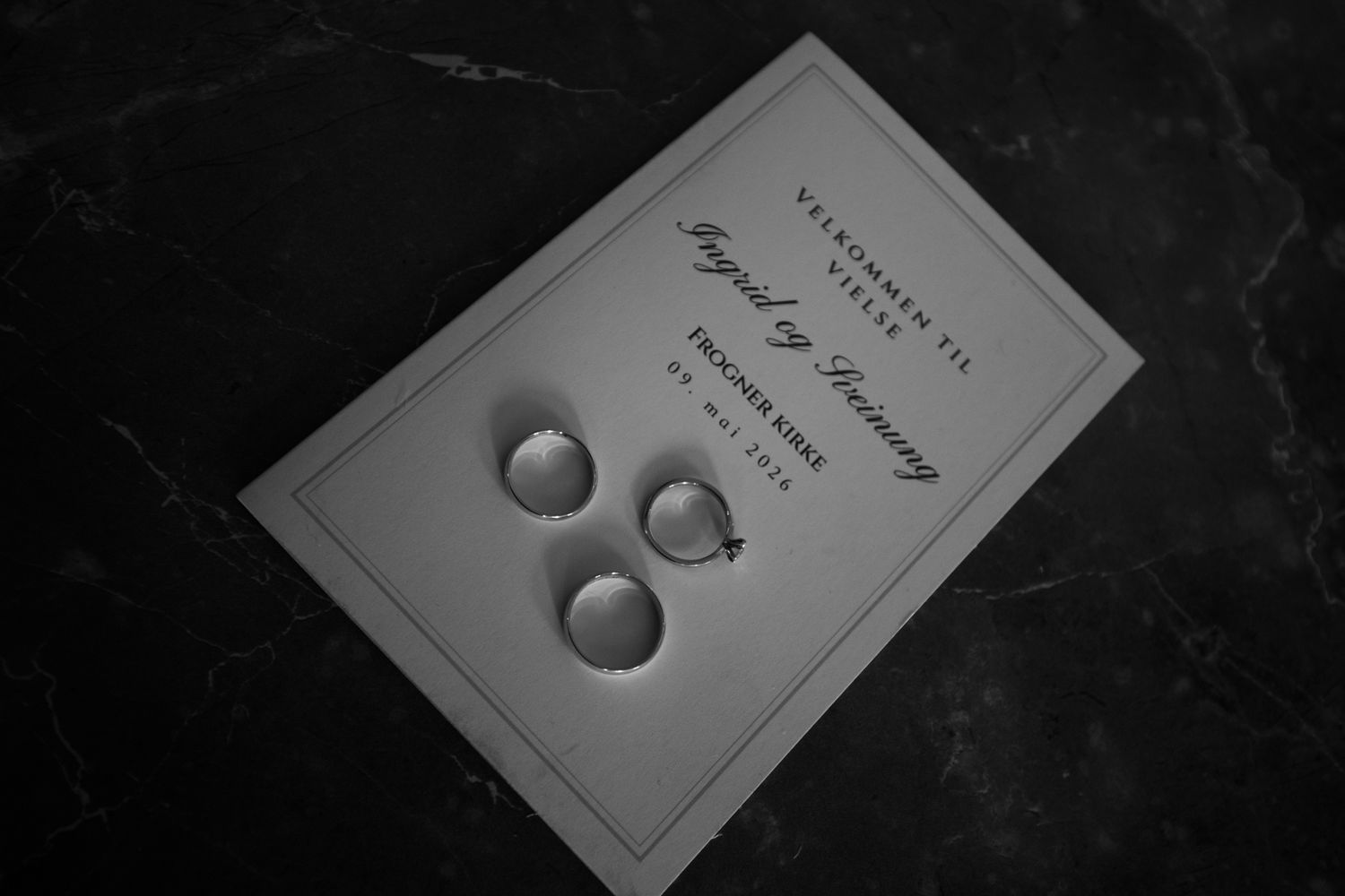 Black and white image of wedding rings resting on a ceremony program card.