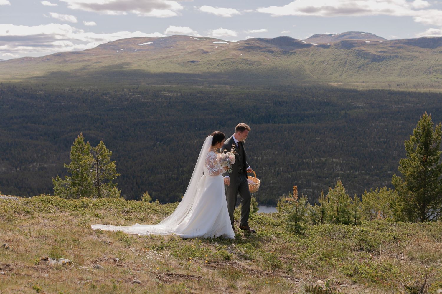 A scenic mountain wedding photoshoot with dramatic clouds and rolling hills in the background.
