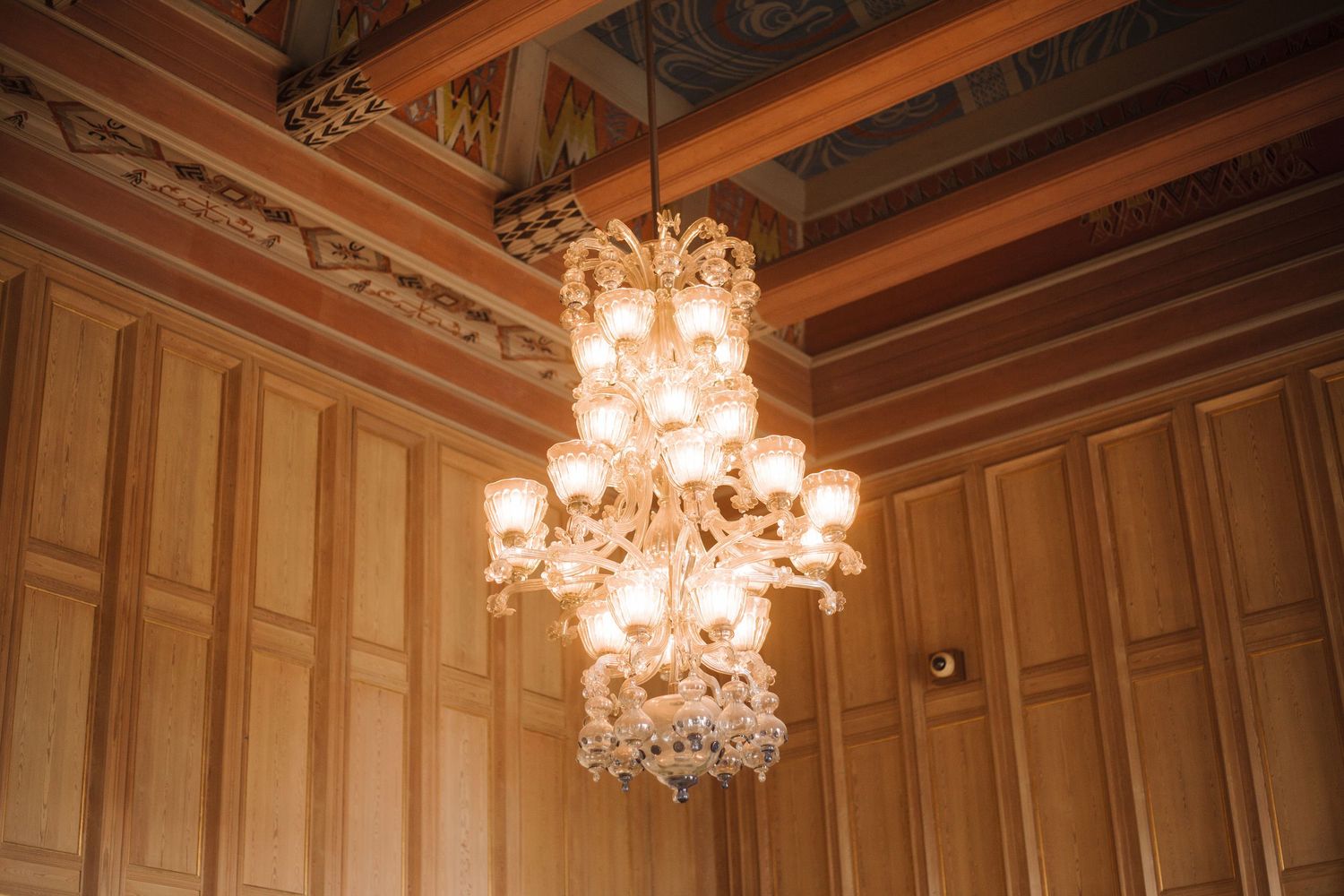 Elegant ballroom interior with ornate chandeliers and wooden paneled ceiling.
