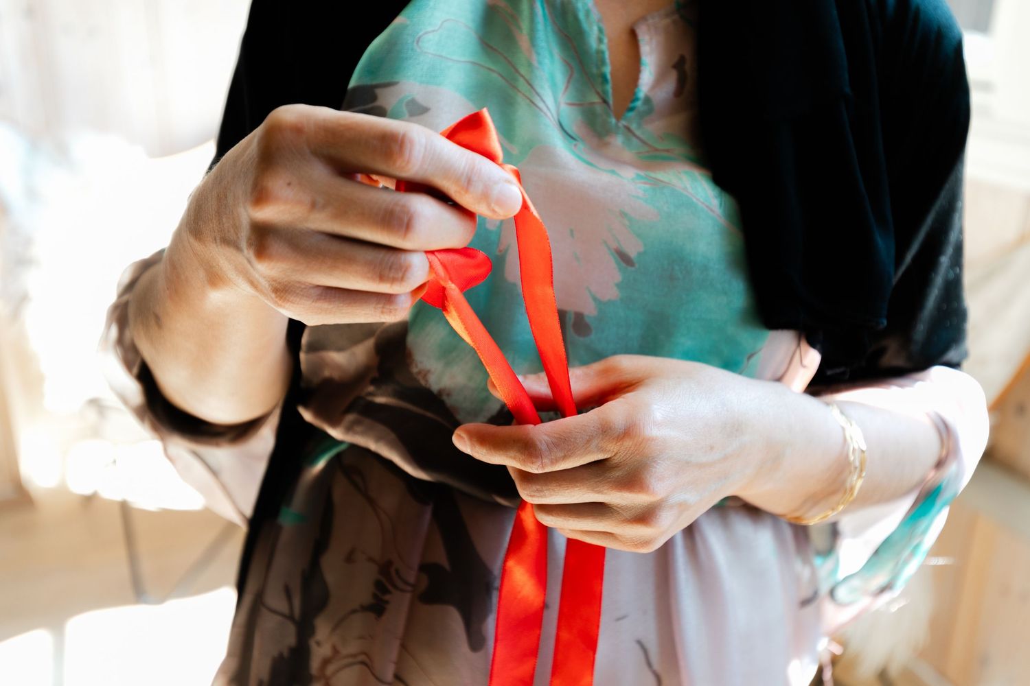 Close-up view of hands holding red gift ribbons or decorations.