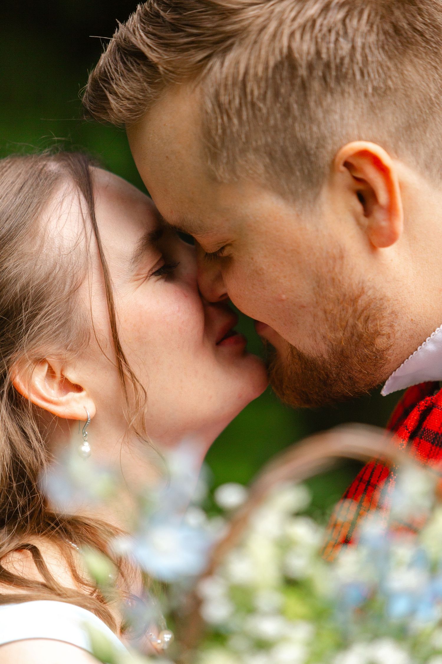 Close-up artistic portrait showing a tender romantic moment among blue flowers.