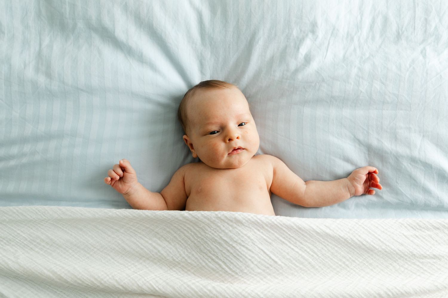Artistic shots of a baby lying peacefully on light colored bedding.
