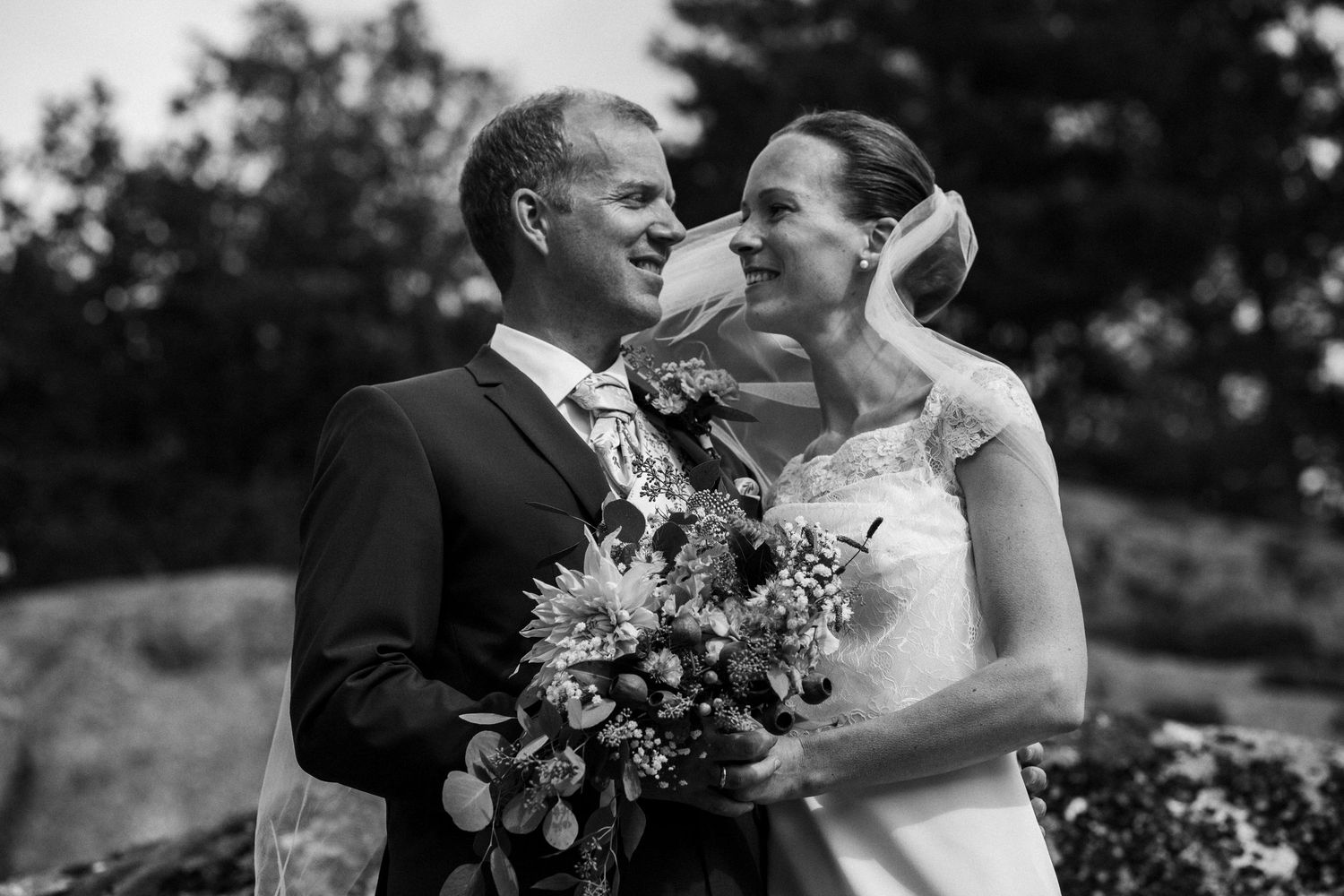 Black and white romantic portraits of a couple in formal wedding attire outdoors.