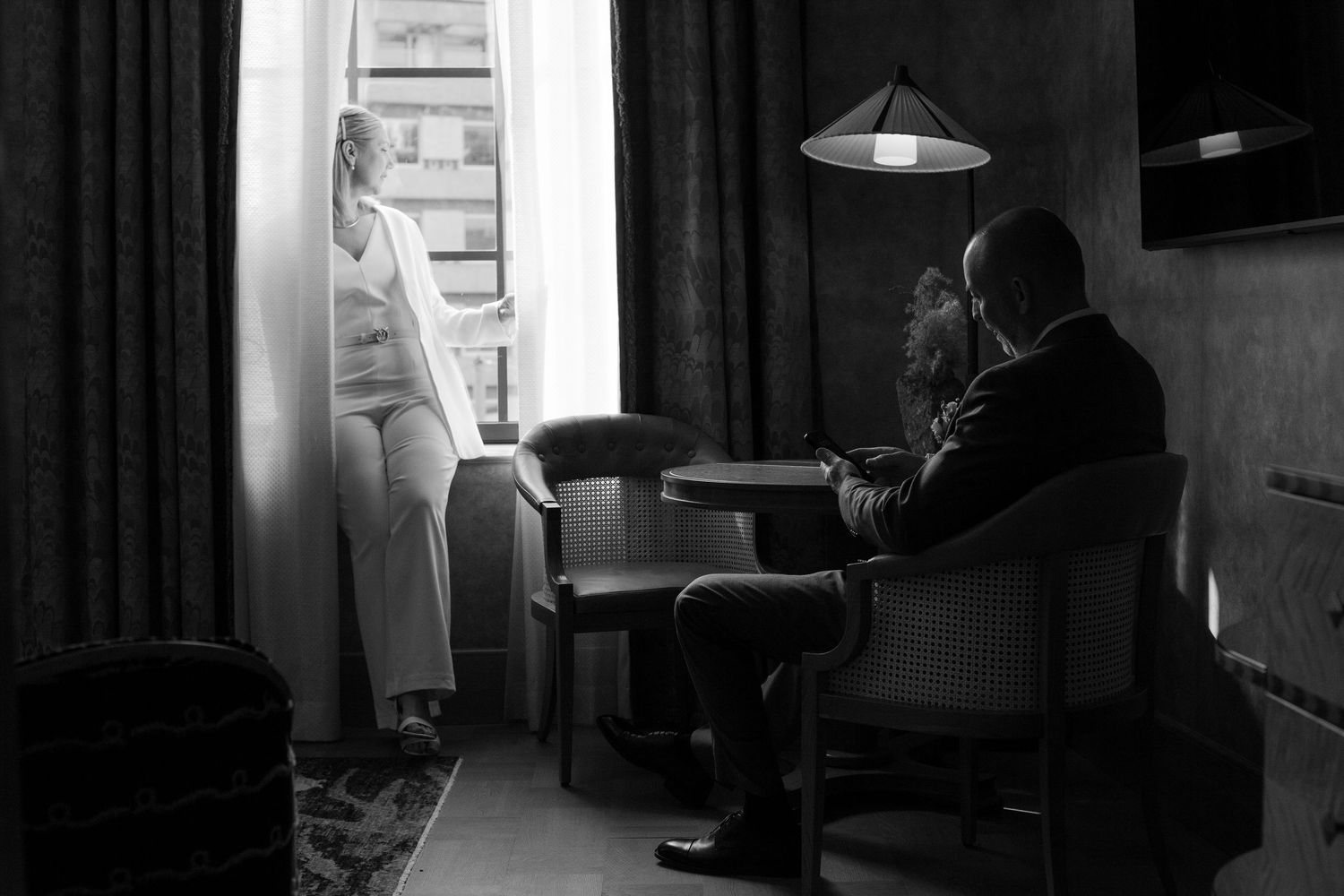 Black and white photograph of a lounge setting with dramatic window lighting.