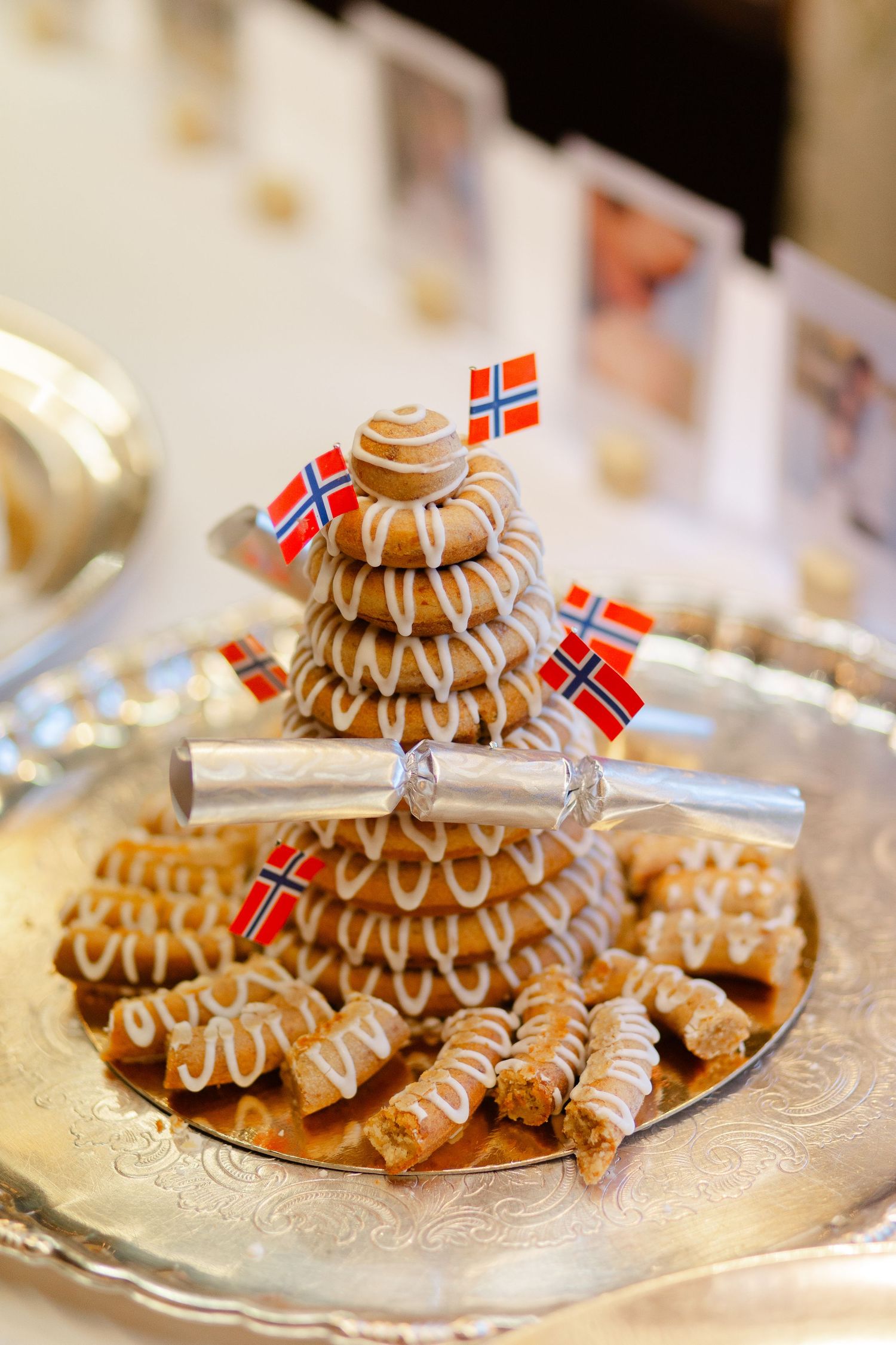 Traditional Norwegian kransekake wedding cake decorated with flags and white icing on a silver platter.