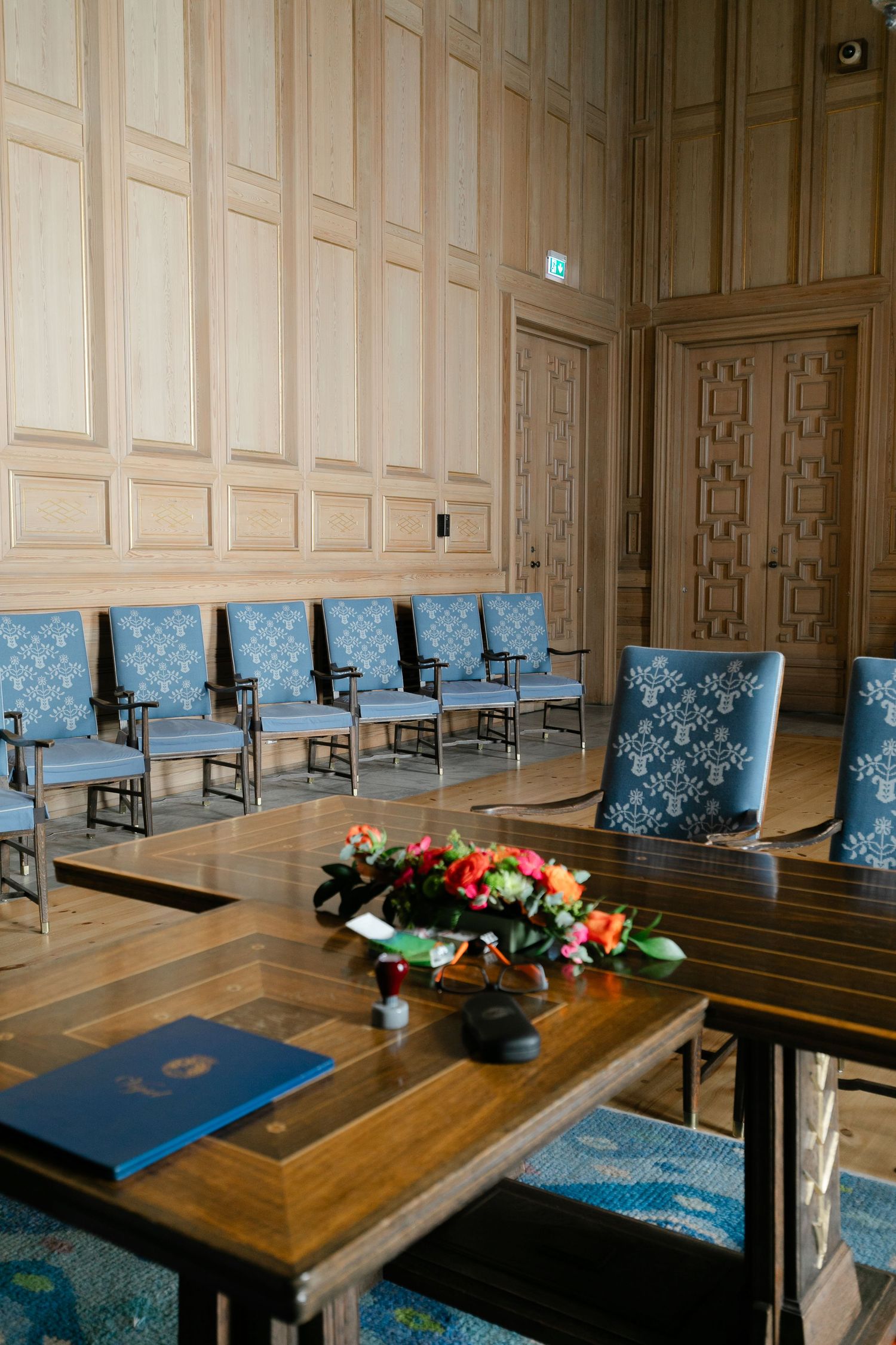 Elegant meeting room with blue upholstered benches and wooden paneled walls.