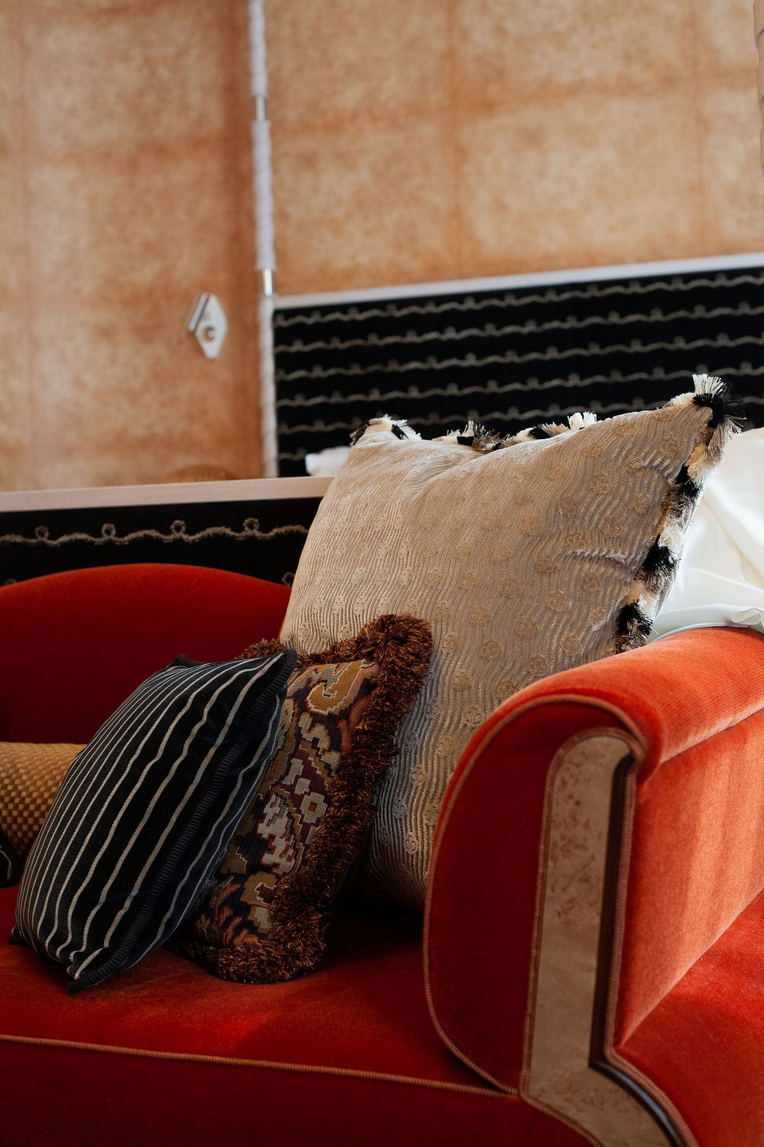 Decorative throw pillows arranged on a plush orange velvet couch.