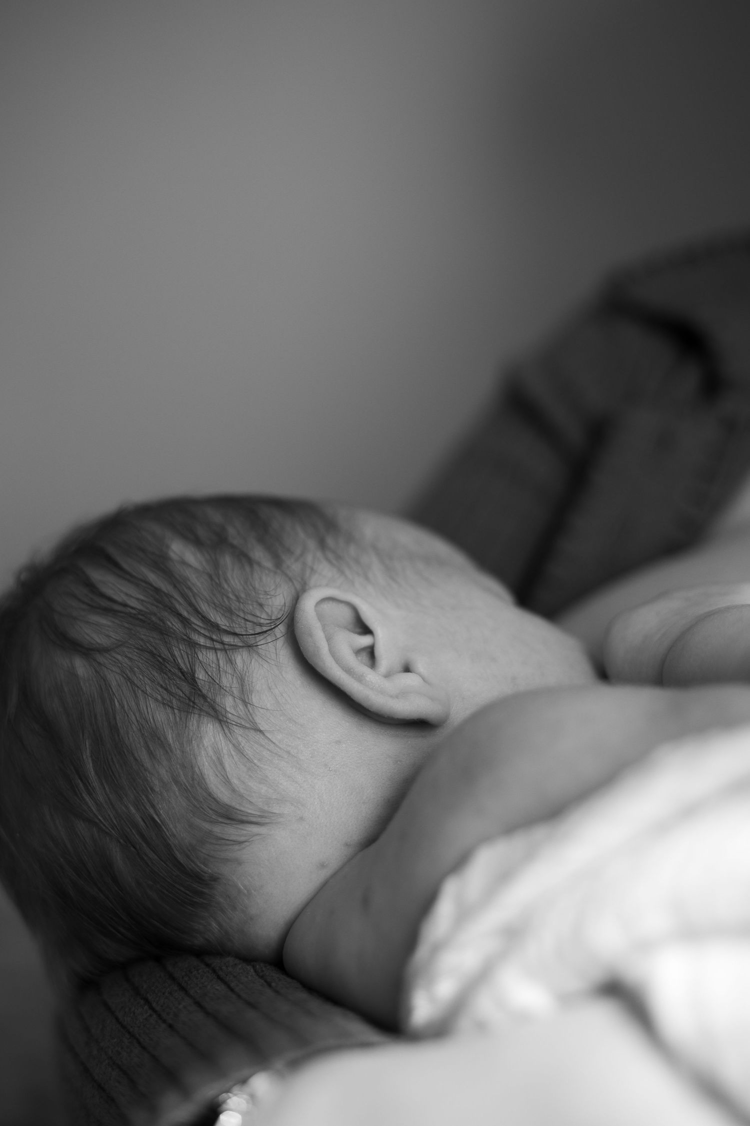 Black and white profile views of a sleeping newborn baby on soft bedding.