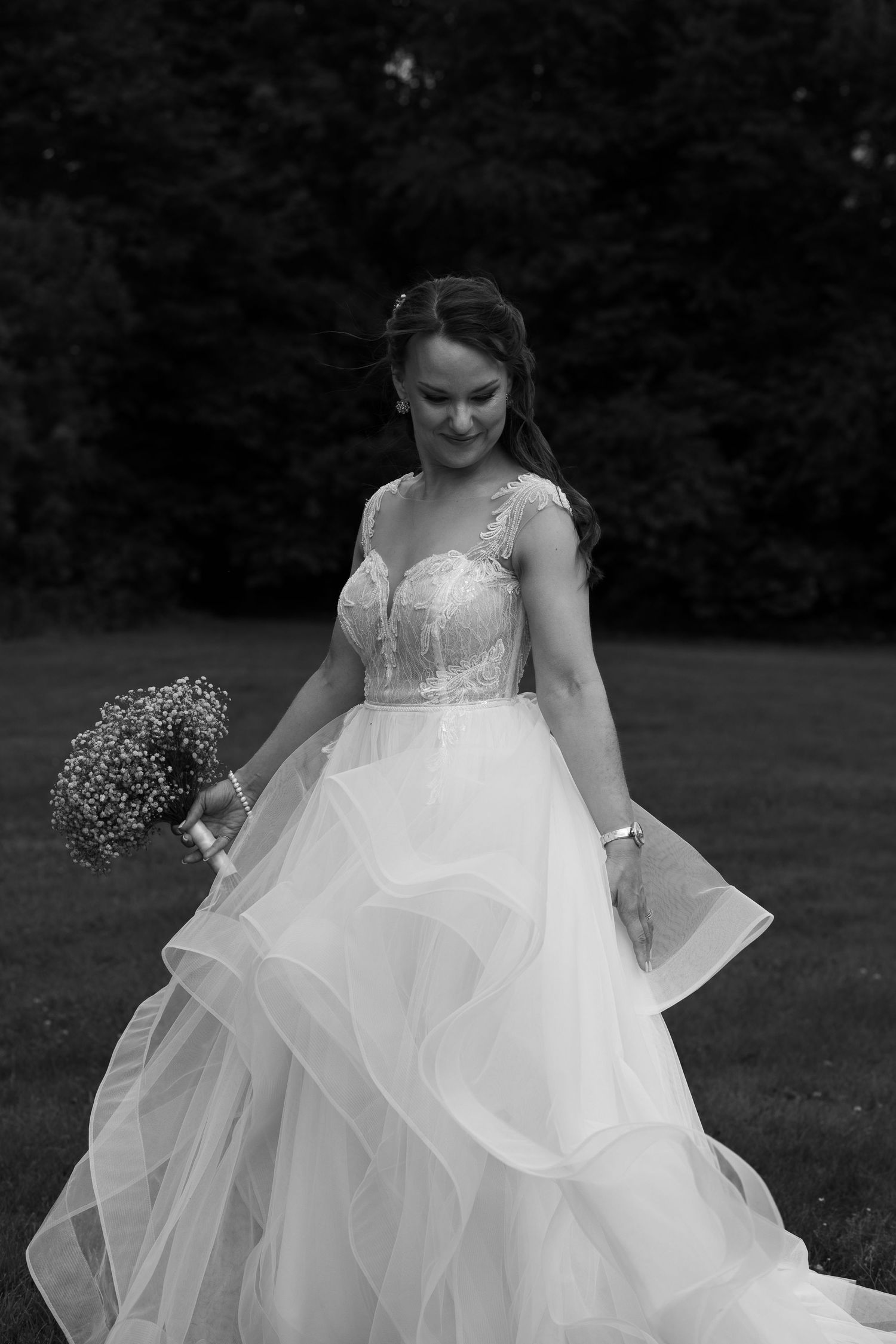 Bride in flowing white ballgown twirls on grassy lawn showing movement of tulle skirt.