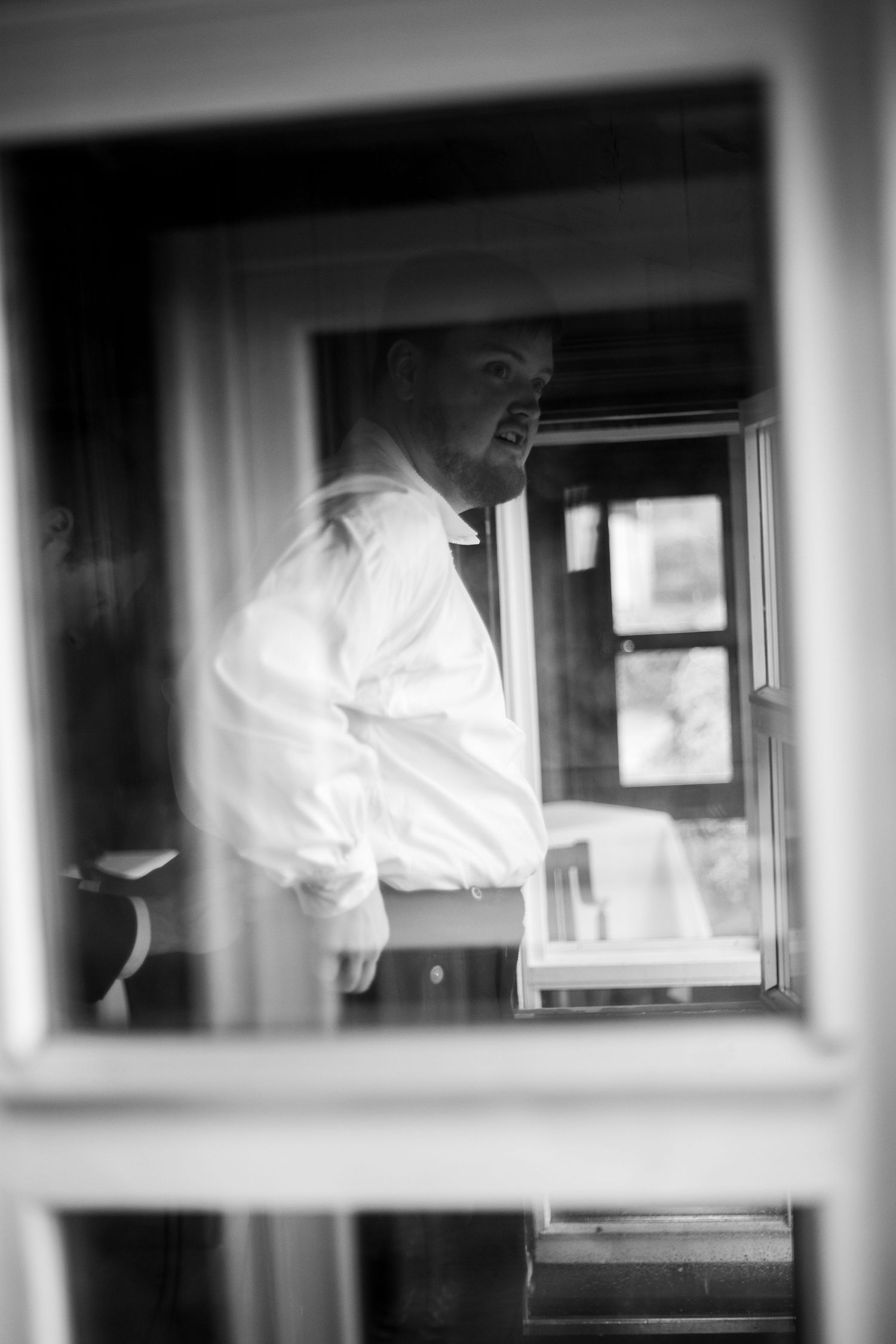 Black and white photo of wedding preparations seen through window panes.