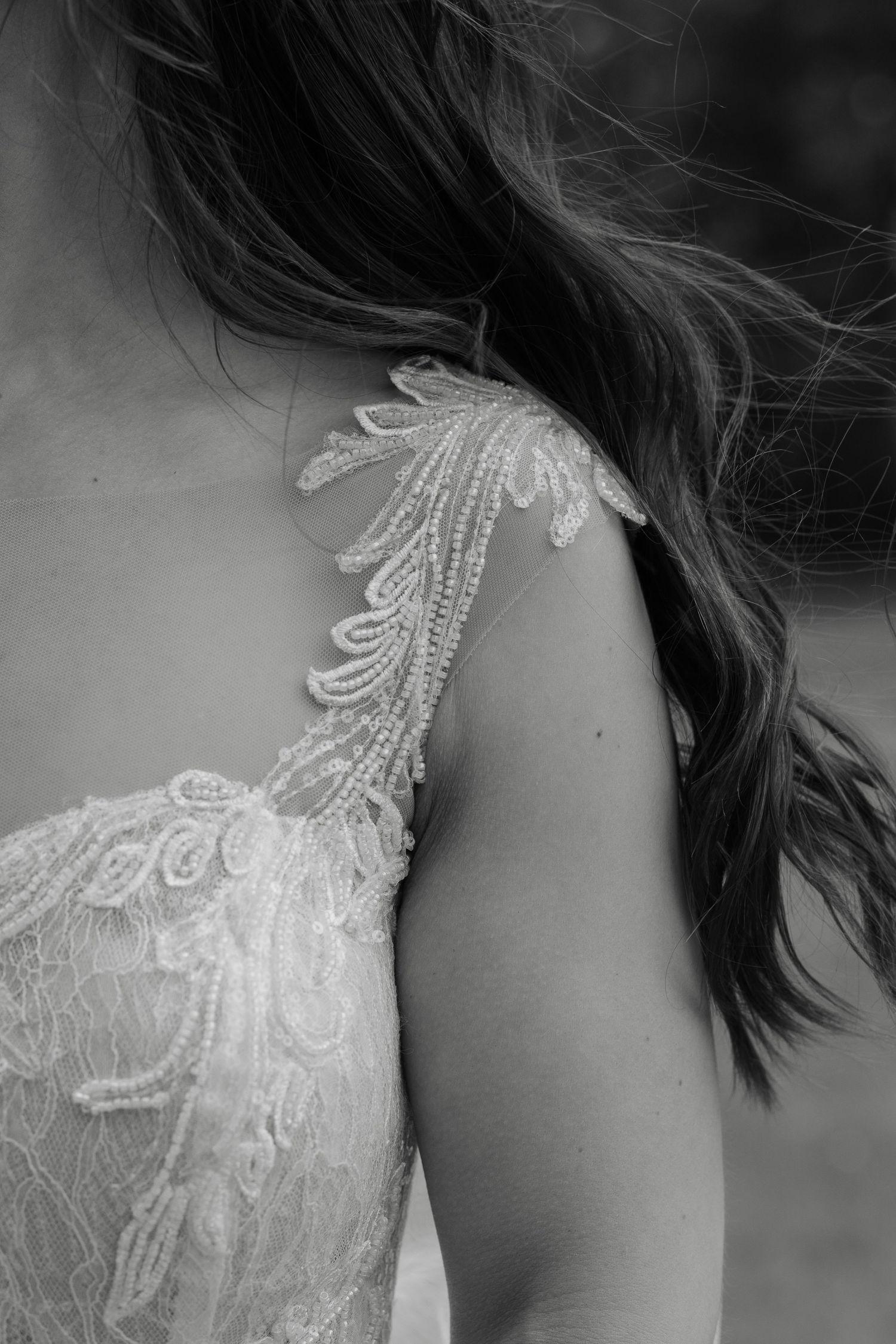 Detailed black and white shot of intricate lace pattern on wedding dress strap.