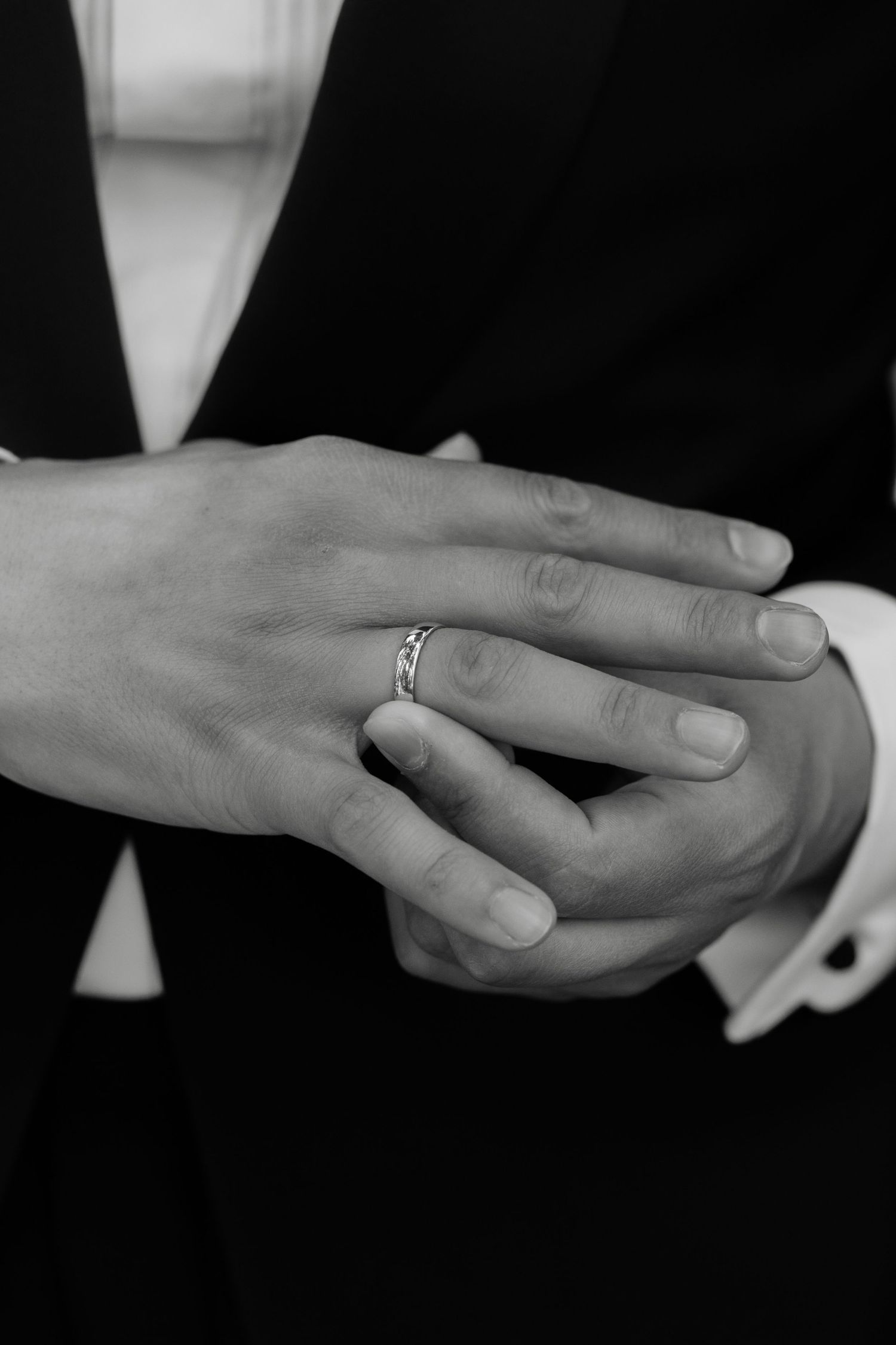 Close-up sequence of hands exchanging wedding rings in black and white.