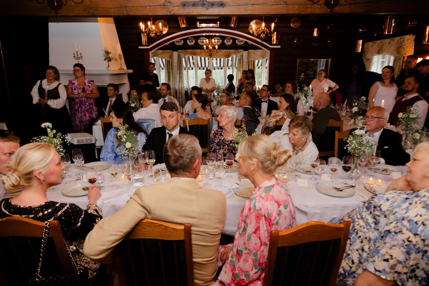Wedding reception dinner scene with guests seated at decorated tables.