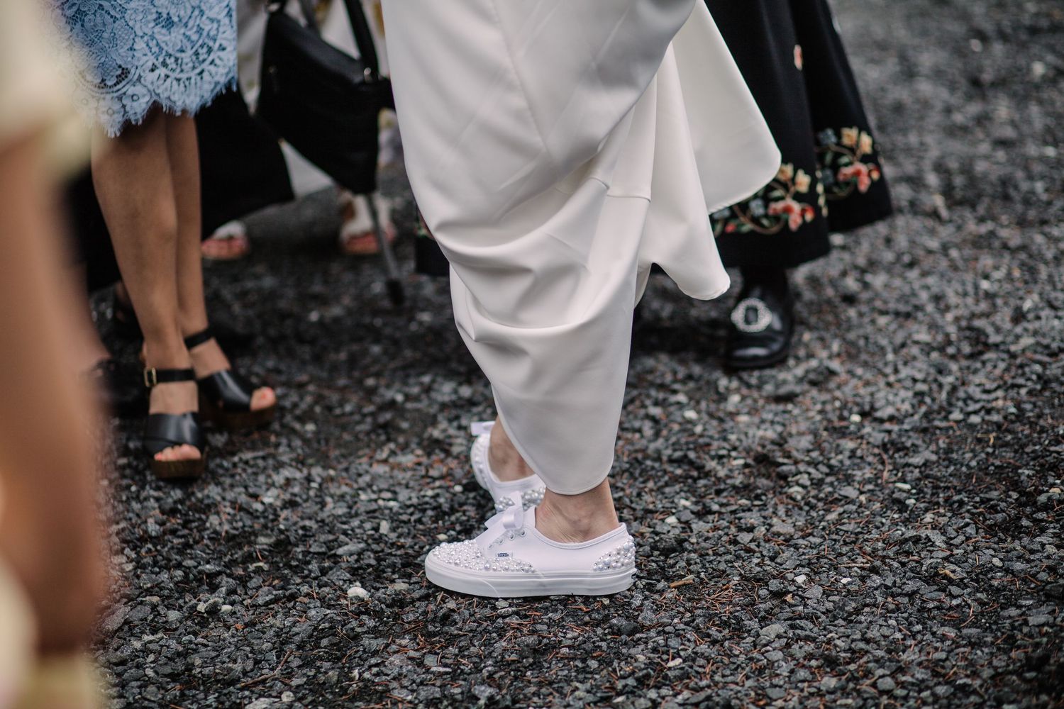 White wedding shoes and dress hem walking on gravel ground.