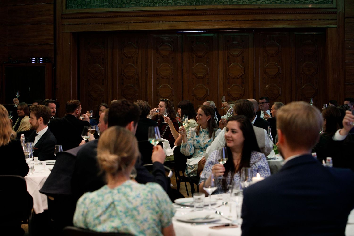 Guests seated at dining tables during an elegant indoor banquet.
