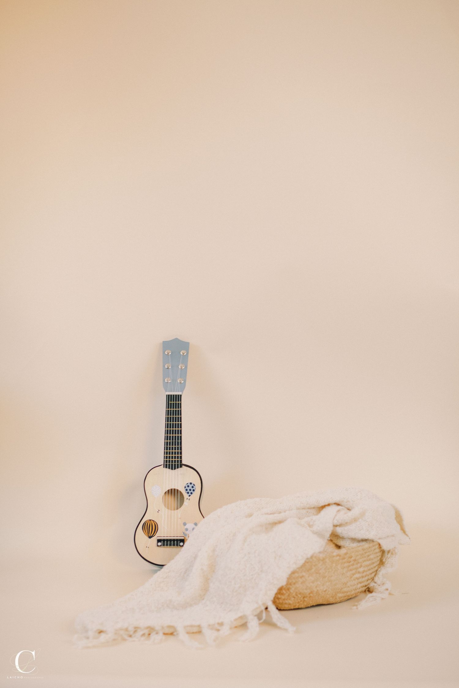 White ukulele laying on soft beige fabric in minimalist style.