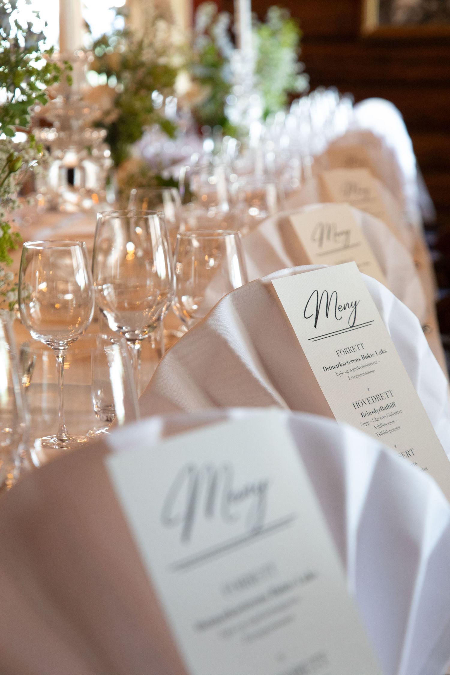 Elegant wedding reception table settings with white napkins and menu cards.