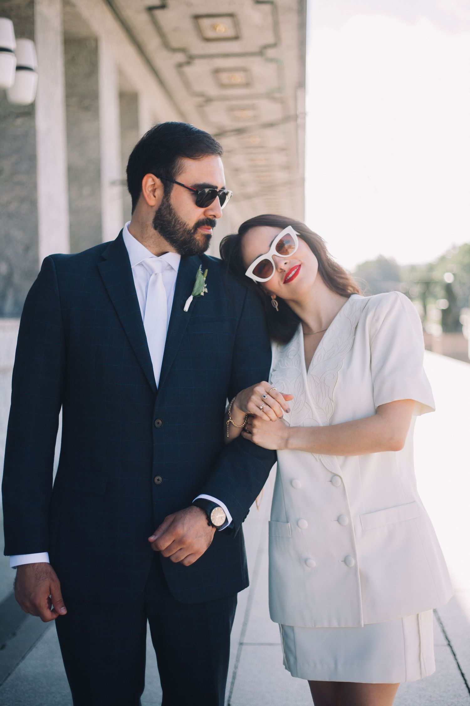 Stylish couple in black and white outfits posing against architectural columns.